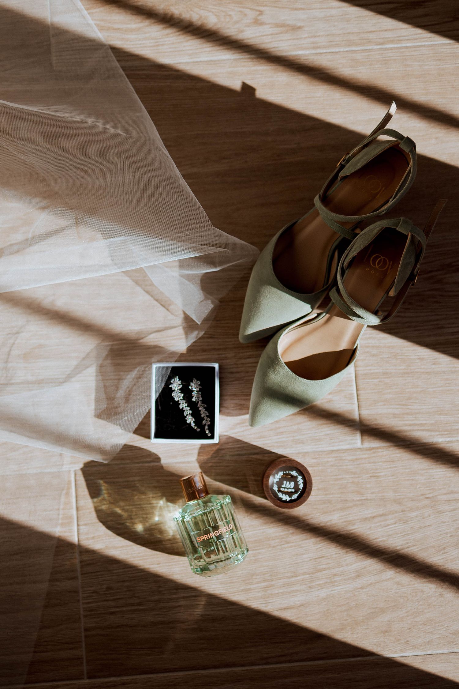 Sunlight casts dramatic shadows across wooden floor while illuminating polaroid photos and shoes in artistic composition.