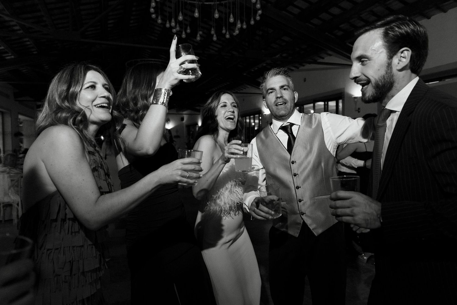 Black and white photo of wedding guests laughing and celebrating at the reception party.