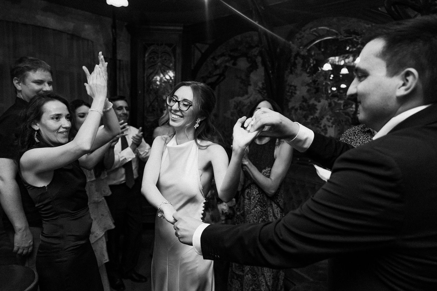 Bride and groom dancing joyfully with guests at a lively black and white wedding reception party.