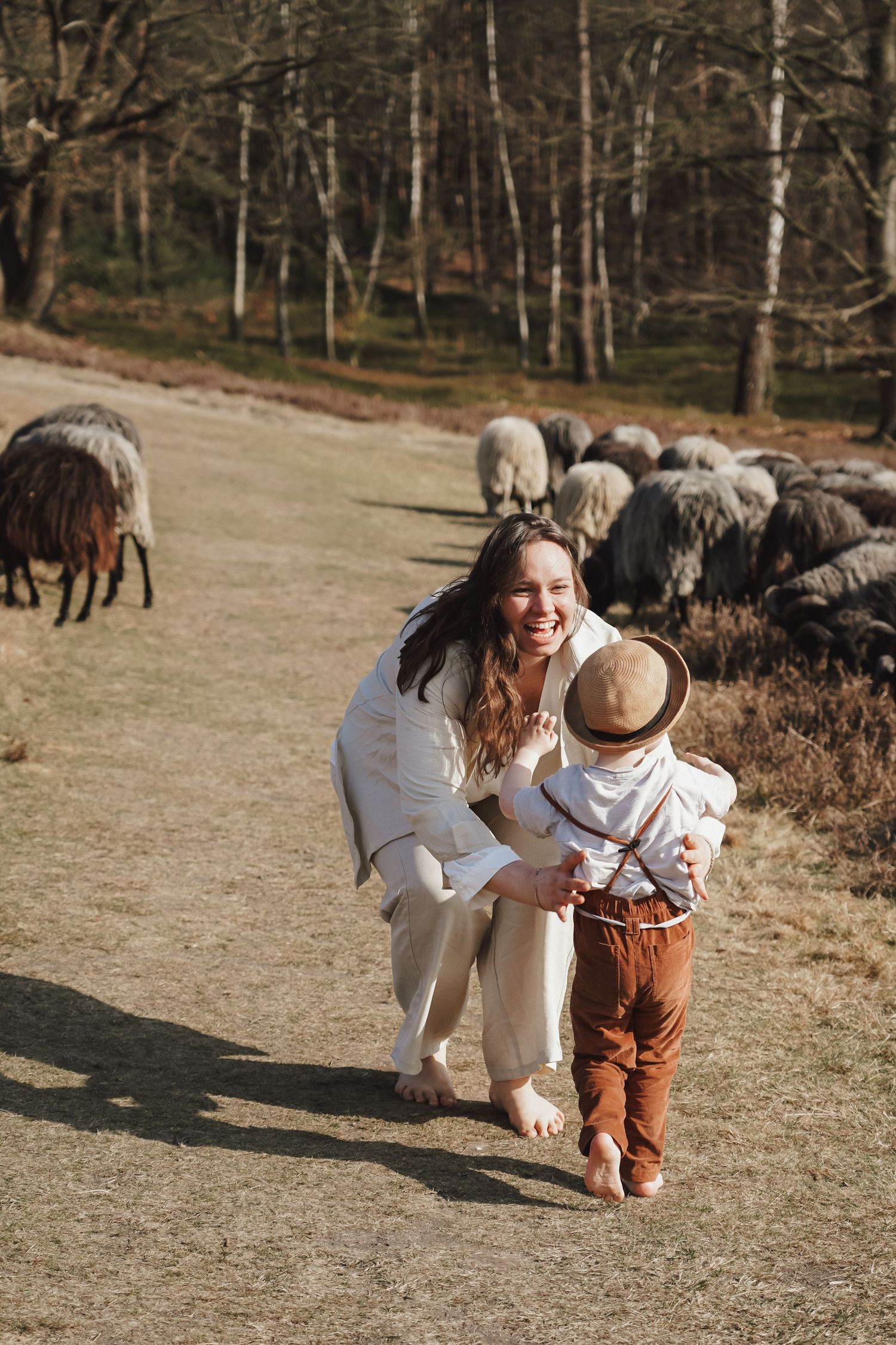 Family enjoying outdoor walk with sheep grazing in background on dirt path.