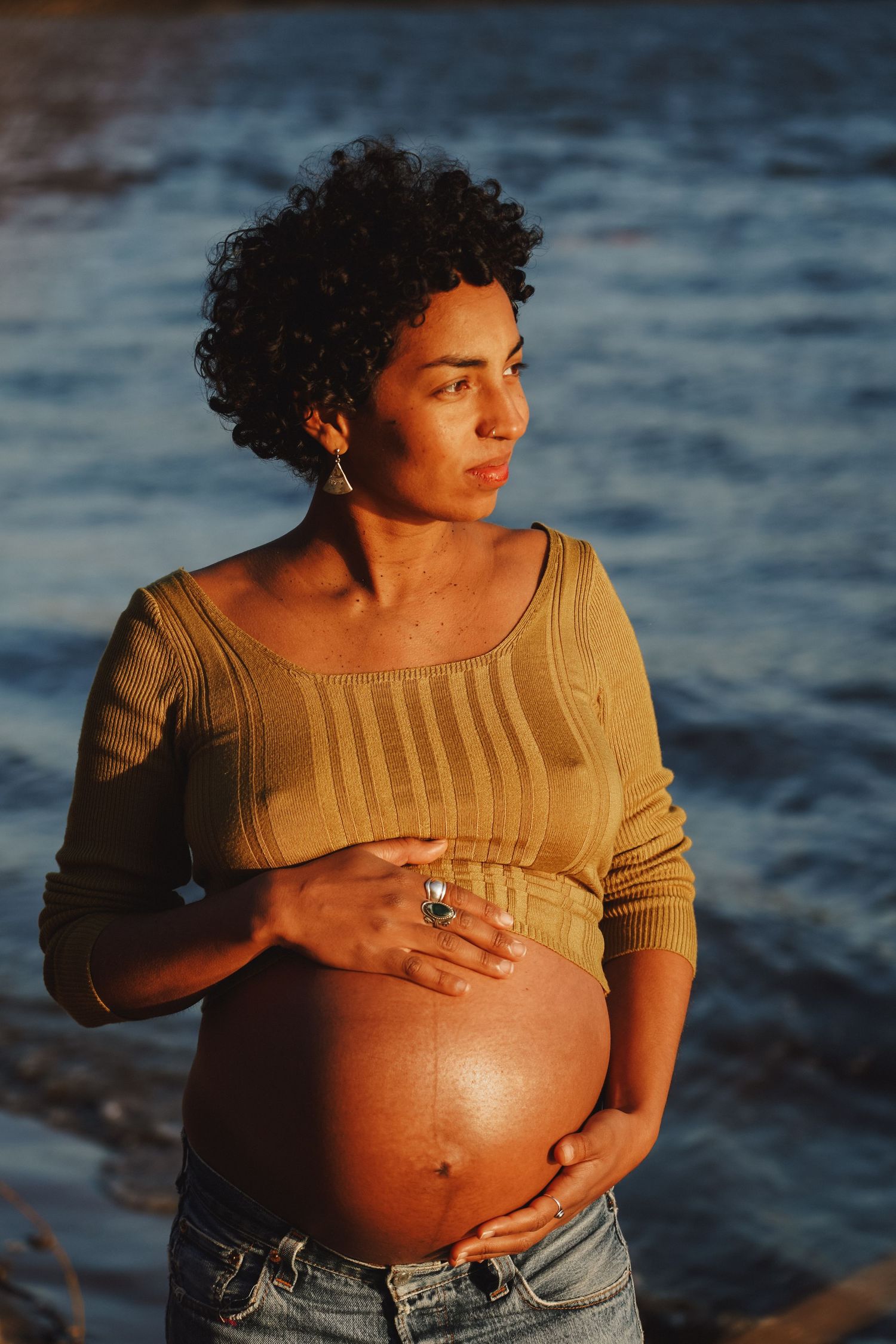 Maternity portrait by the ocean at sunset wearing an olive knit top.