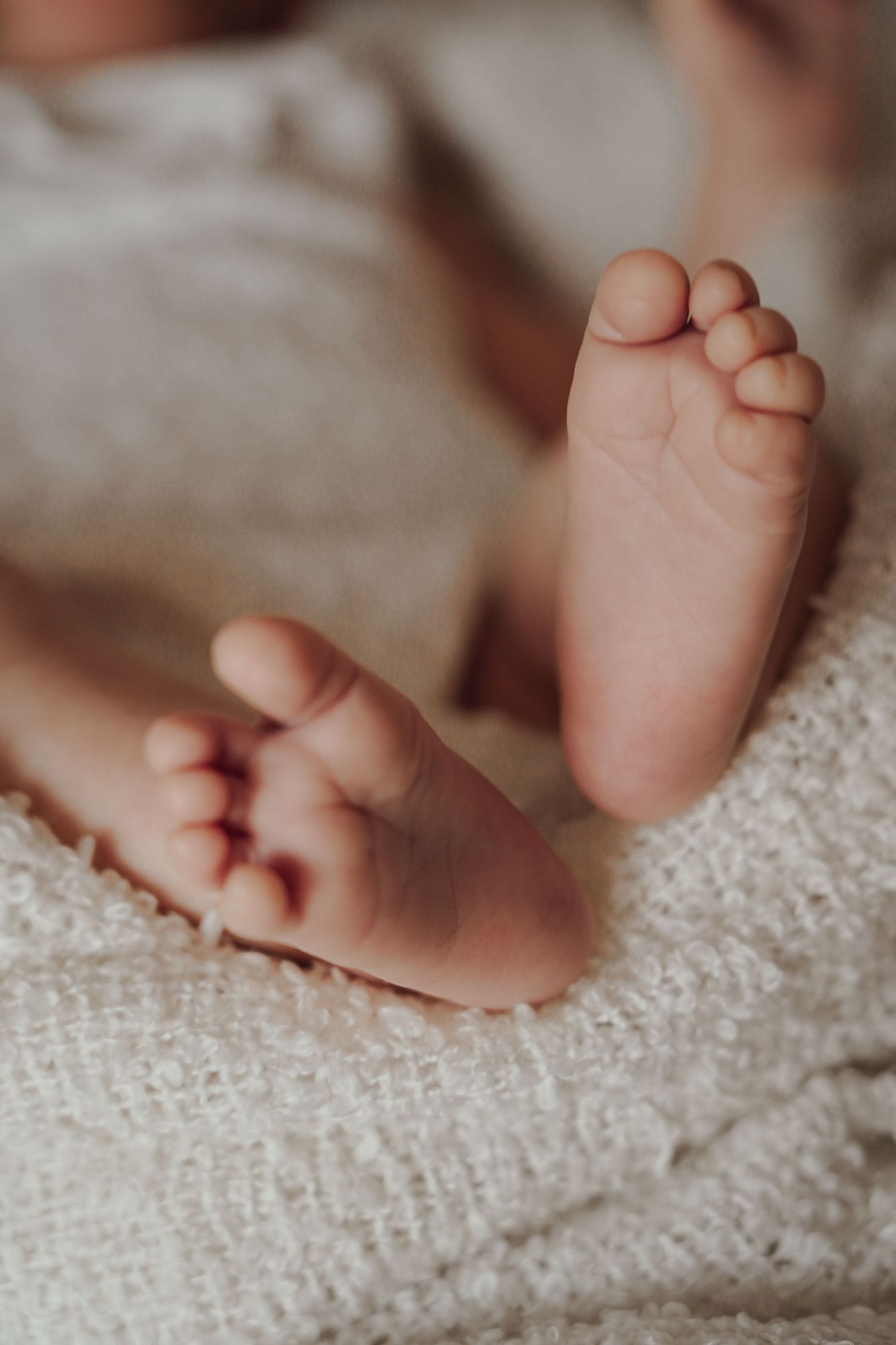 Close-up of tiny baby feet resting on soft textured blanket.
