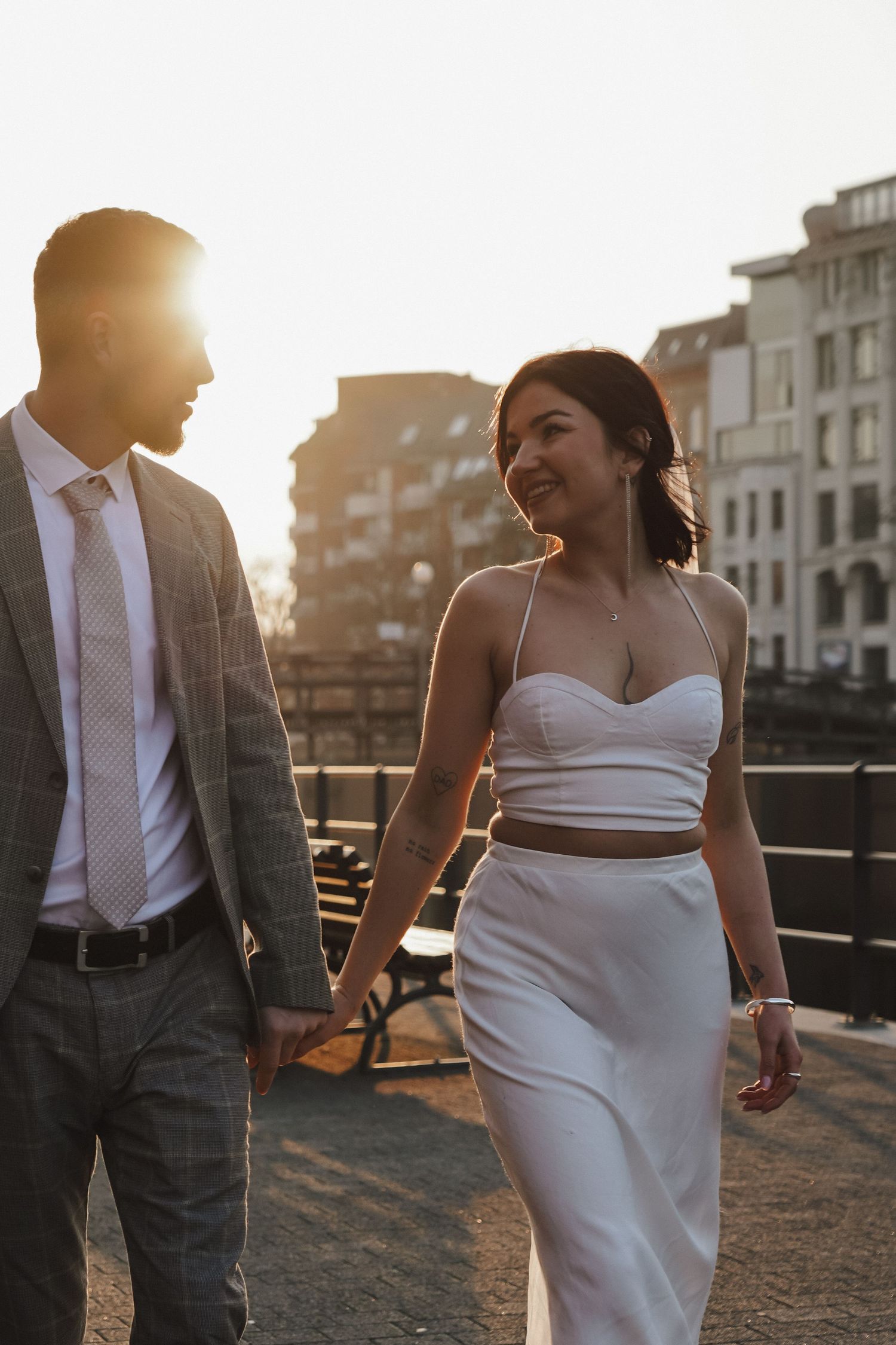 Sunset wedding photo of couple walking together on urban rooftop.