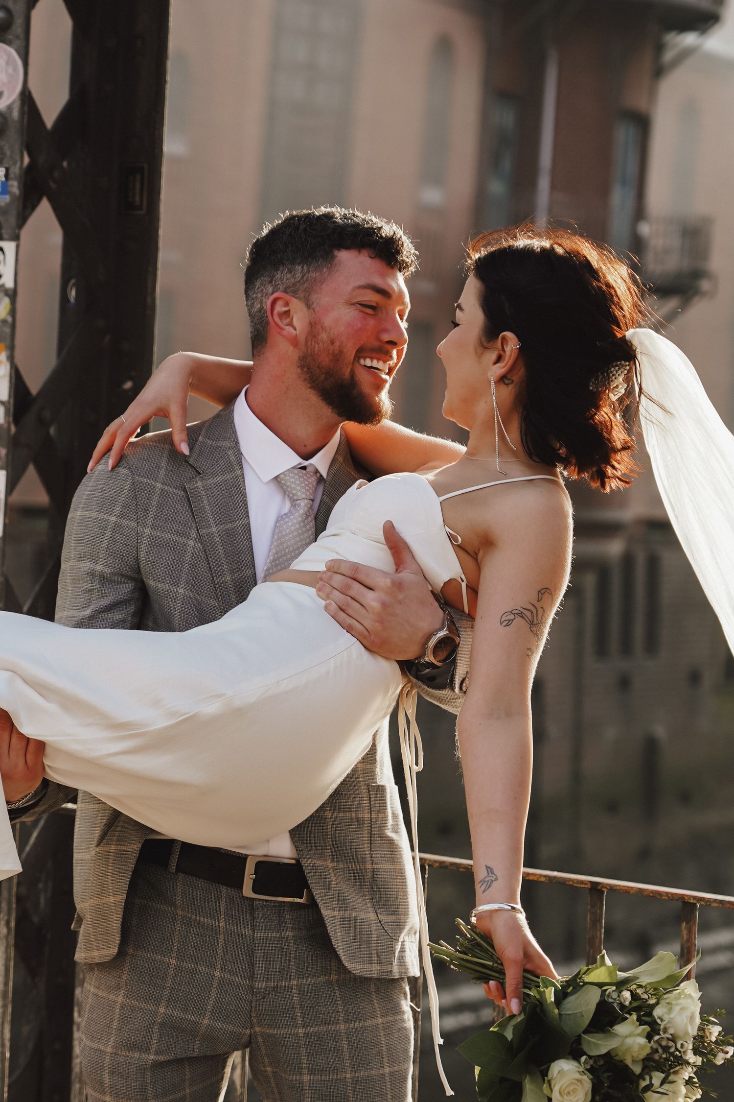A romantic wedding portrait showing a groom carrying his bride in a modern two-piece dress.