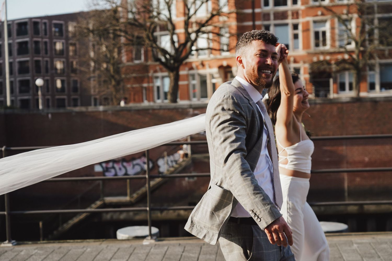 Wedding couple dancing on wooden deck with bride's veil flowing in the wind.