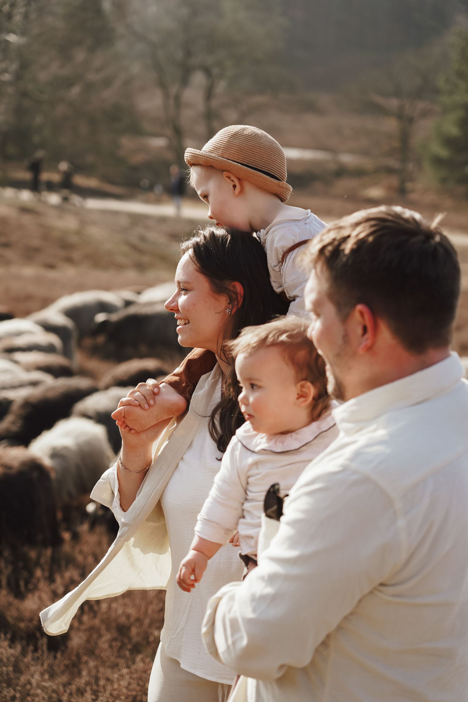Family group watches flock of sheep while standing together outdoors.