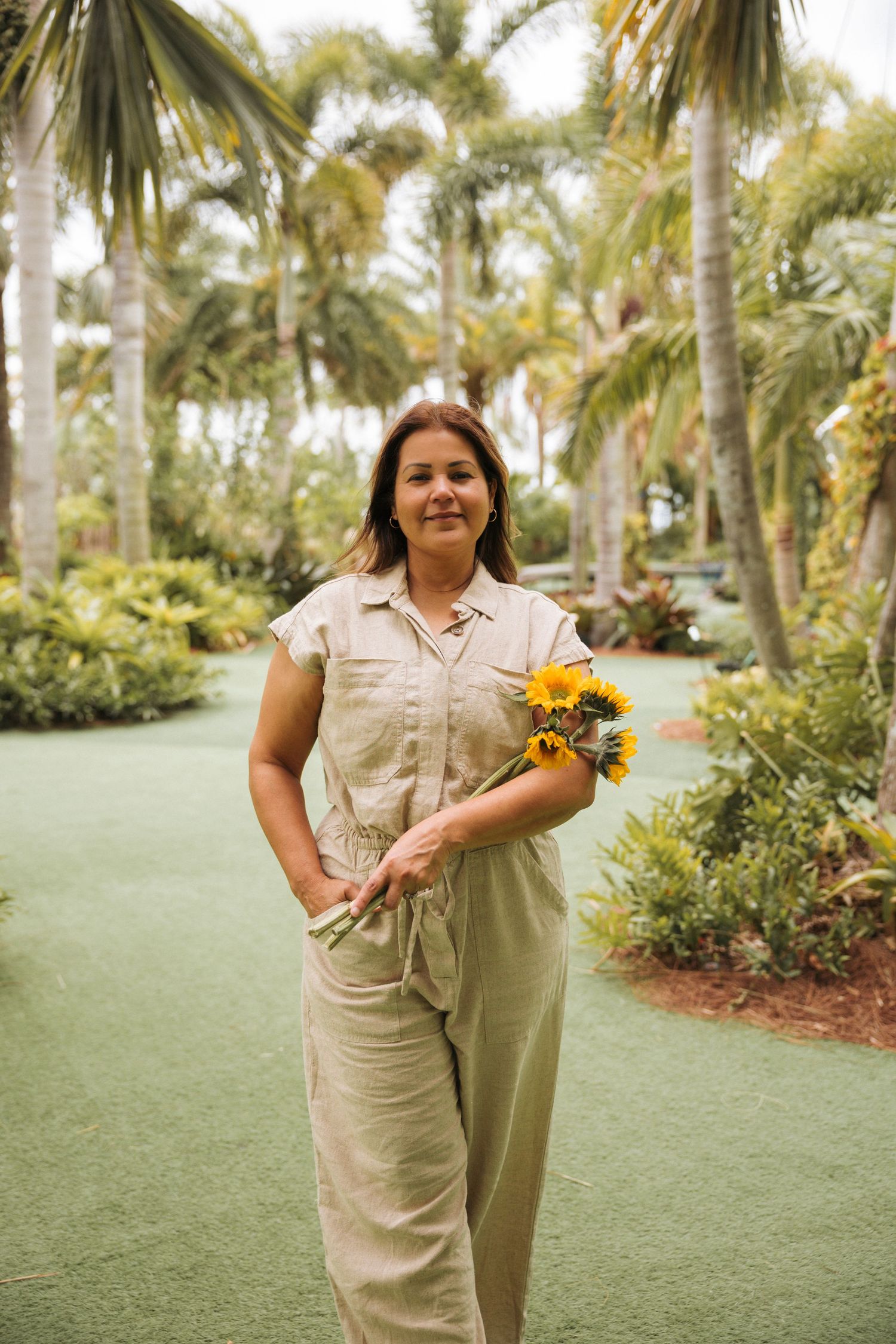 Portrait of a middle aged woman in a nature setting holding a bouquet of sunflowers.