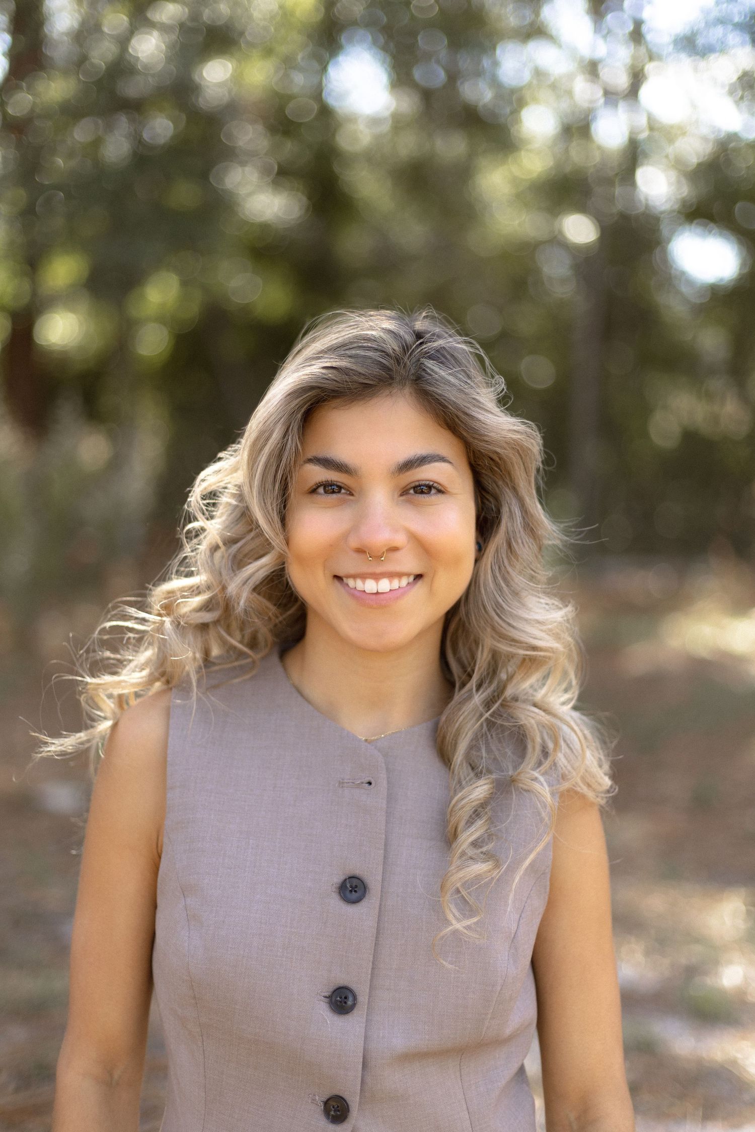 Headshot of a young girl smiling in a nature setting.
