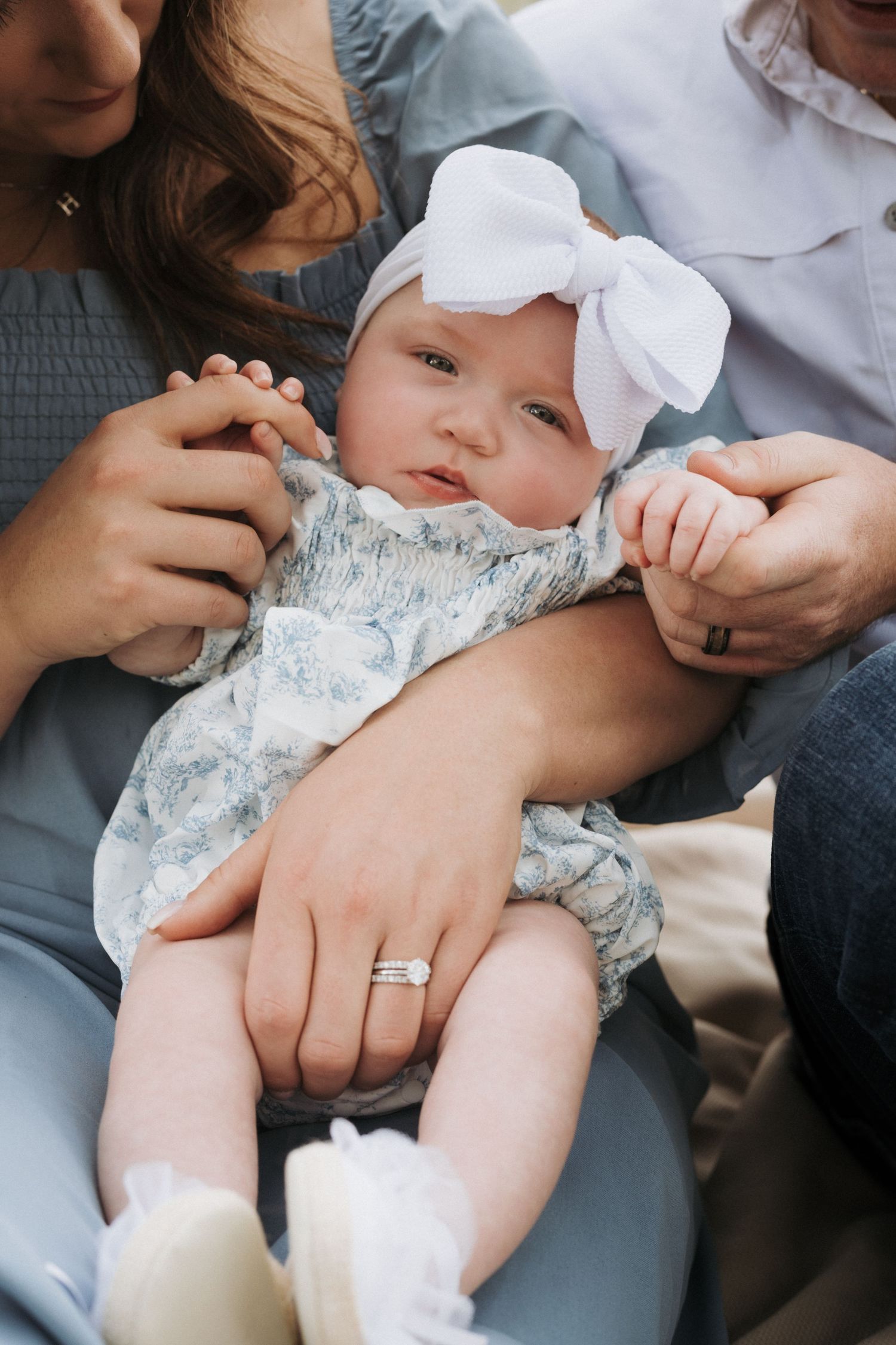 Close up portrait of a family holding their baby but the photo is focused on the baby who is looking directly at camera.