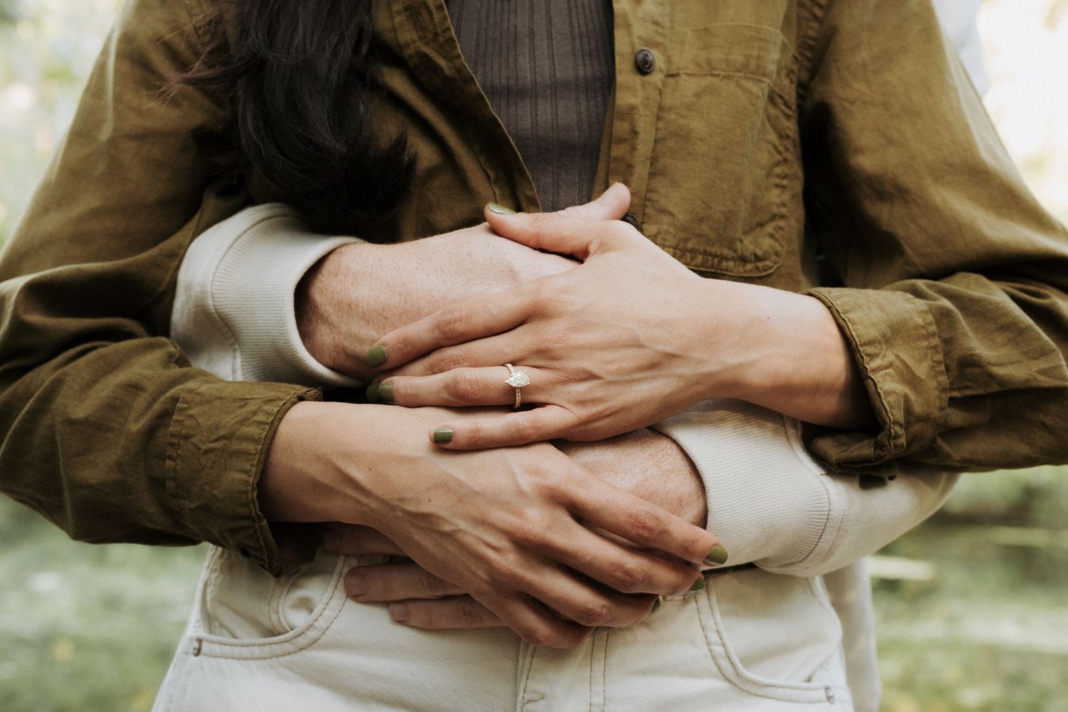Detail photo of couple's hands showcasing engagement ring.