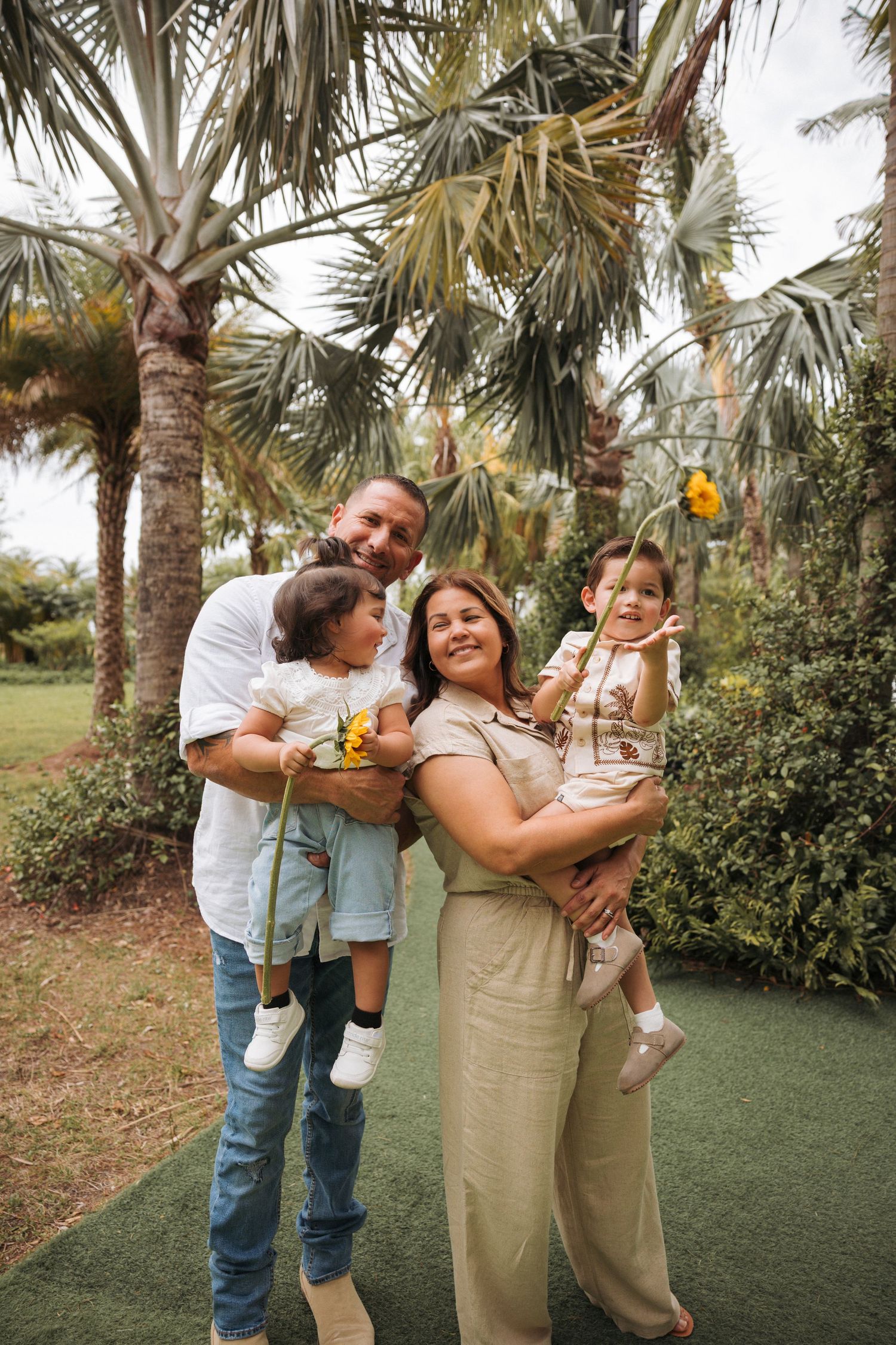 Family portrait of grandparents holding both their grandson and granddaughter. Both children are holding sunflowers.