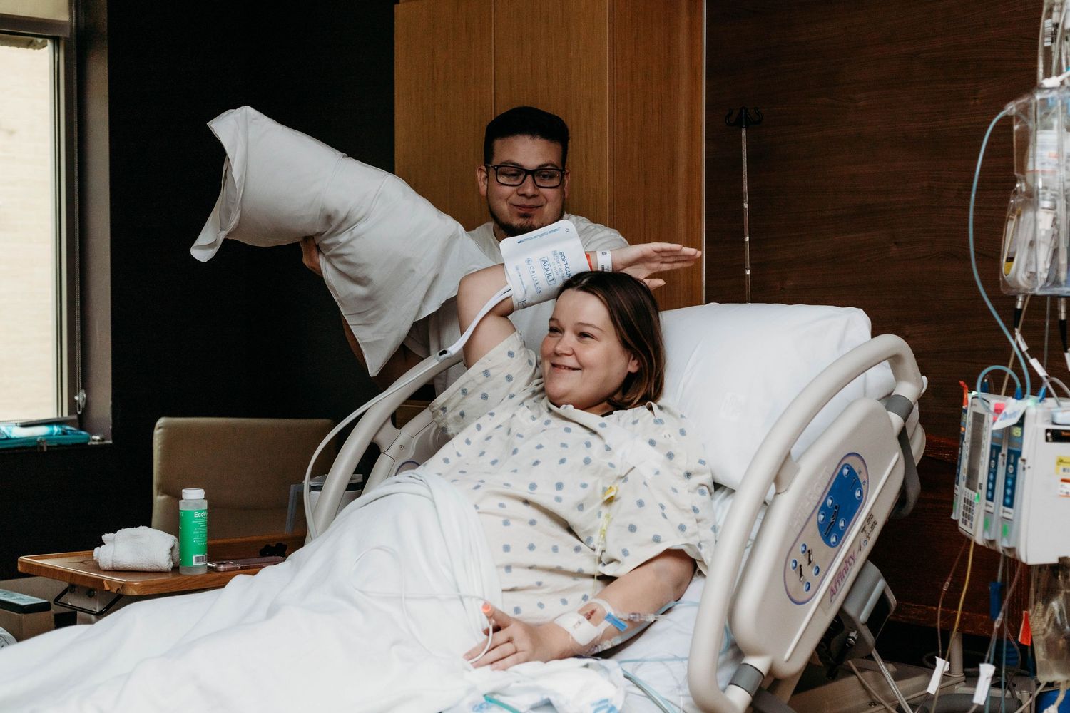 Soon to be father and husband helps adjust pillows for laboring wife
