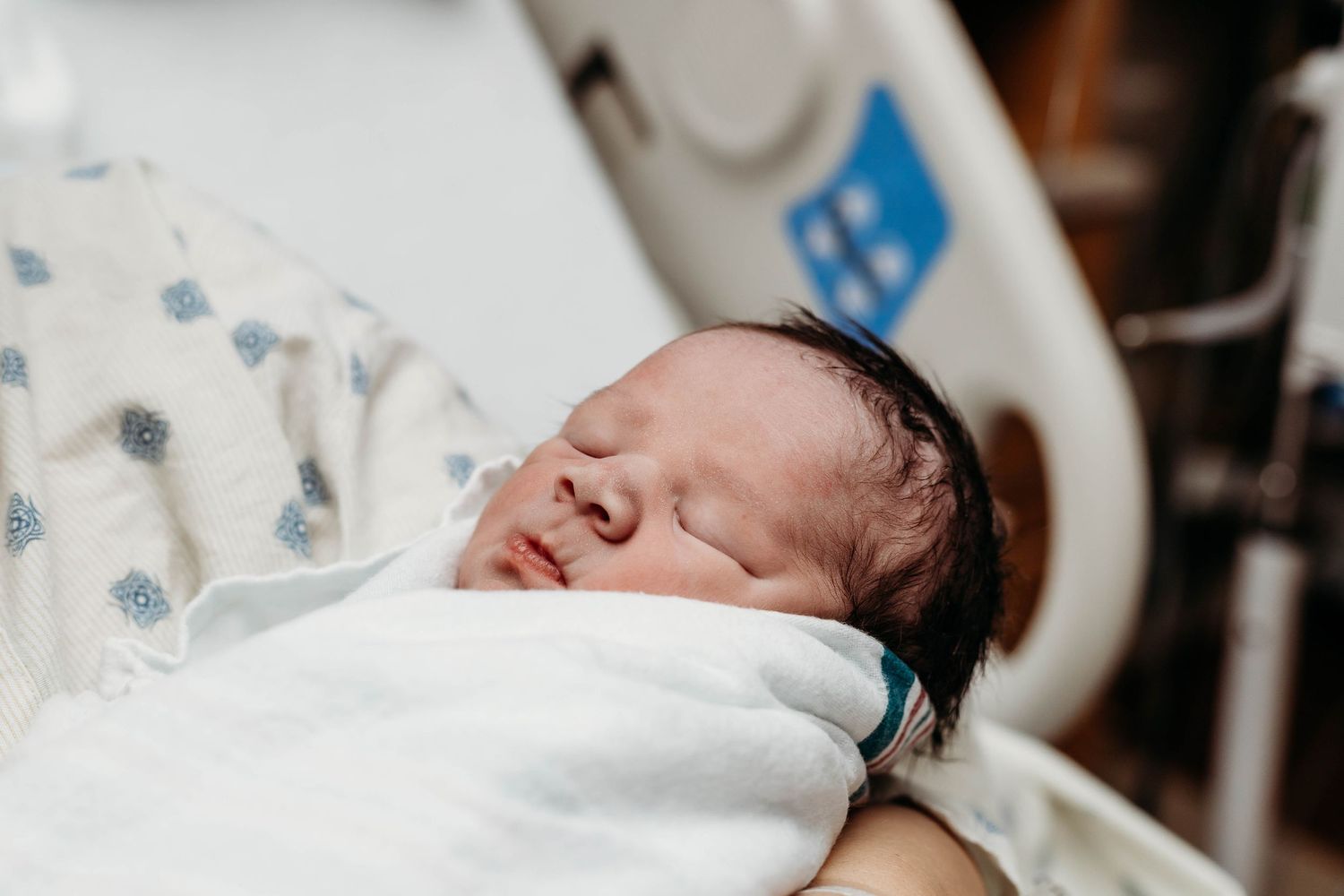 Newborn baby scrunches up face in mothers arms
