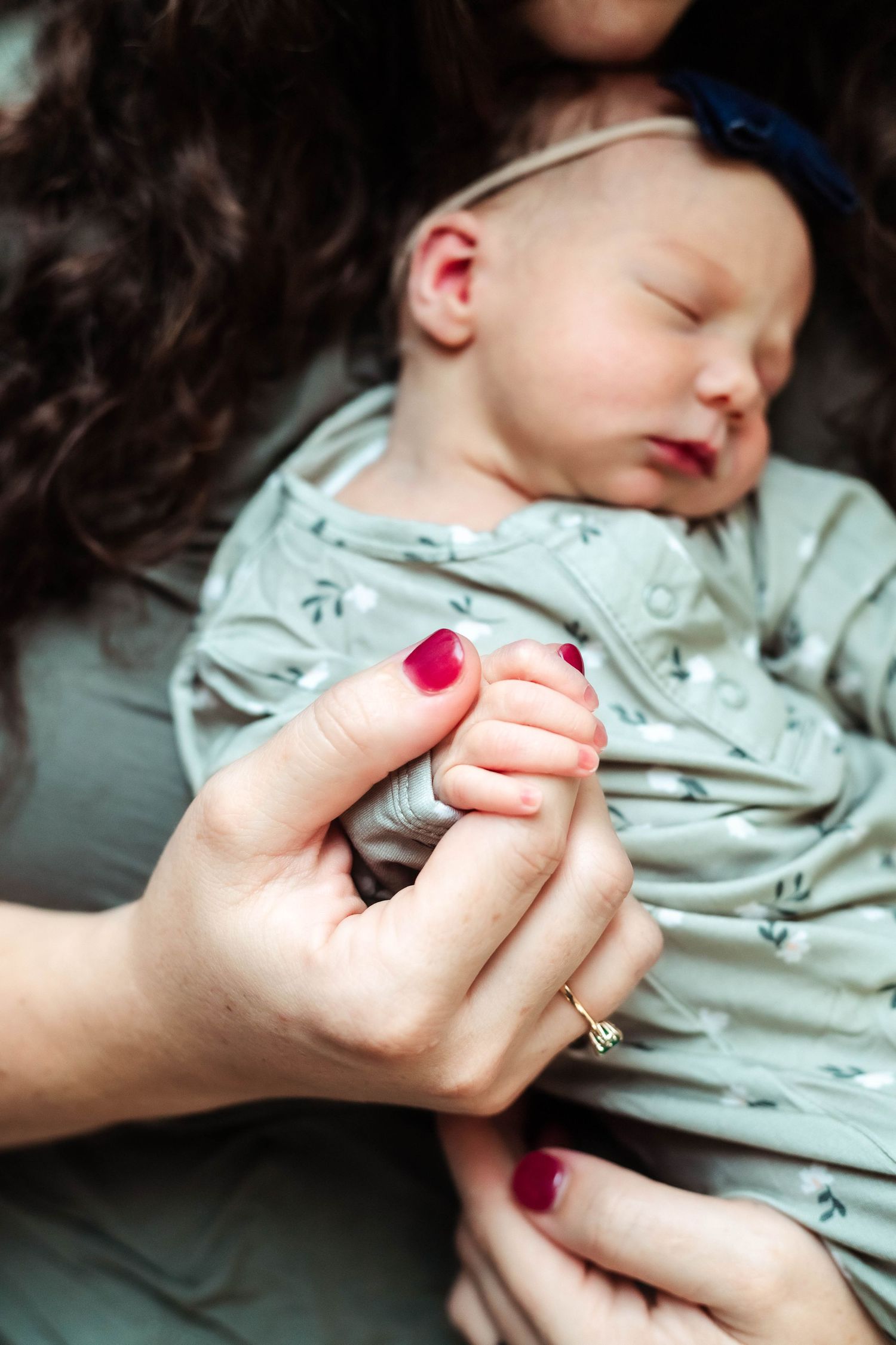 Mother holds newborn baby girl's hand