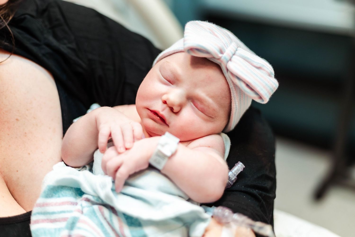 Baby with bow hat on held in mothers arms