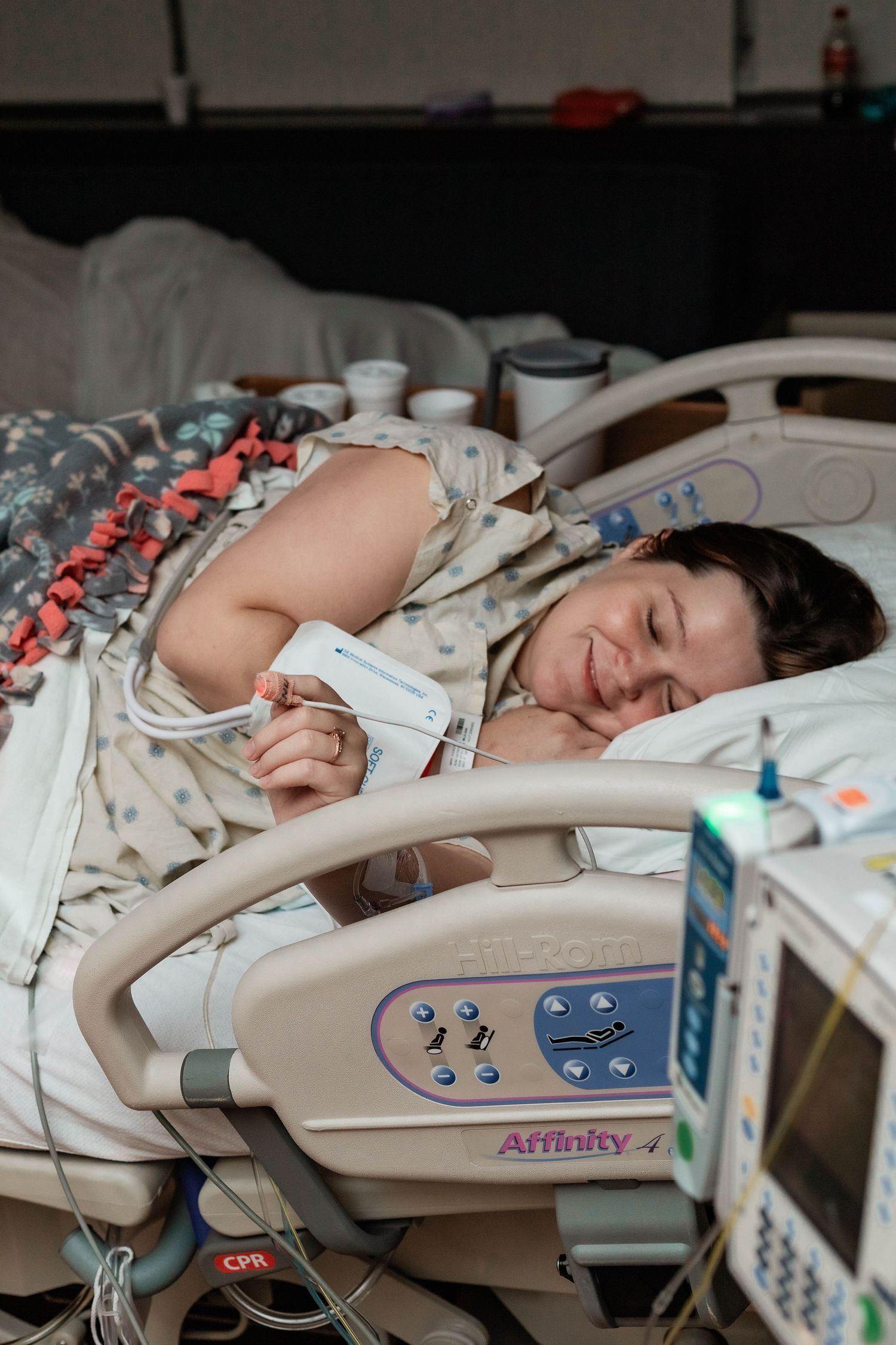 Laboring mother smiles while laying in hospital bed.
