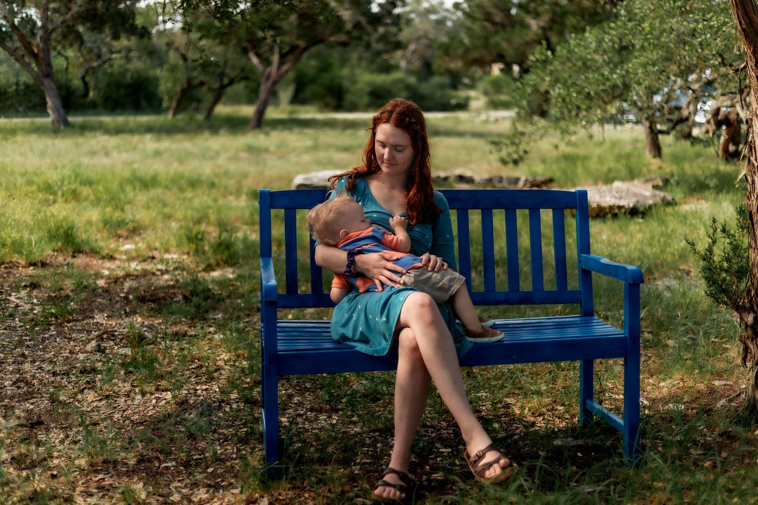 mother nurses kiddo on lap outside