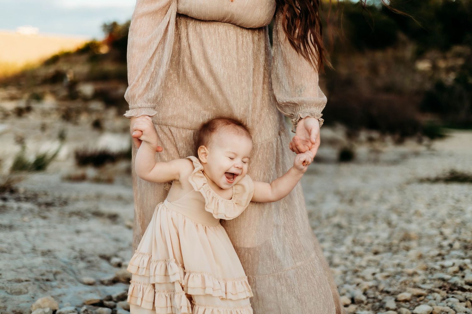 Mother and daughter hold hands while daughter laughs