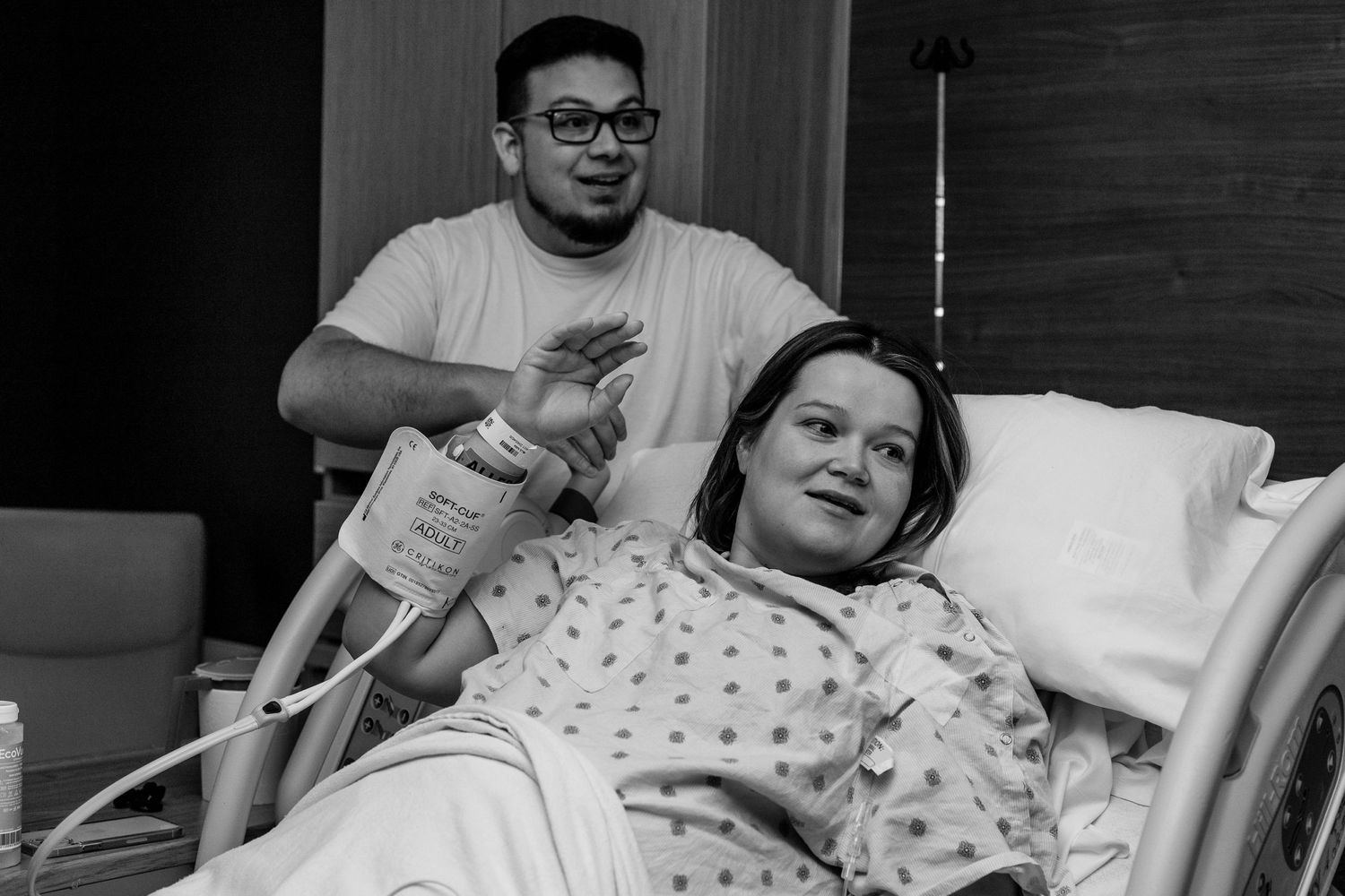 Husband helping wife with her pillow when someone catches their attention in their hospital room