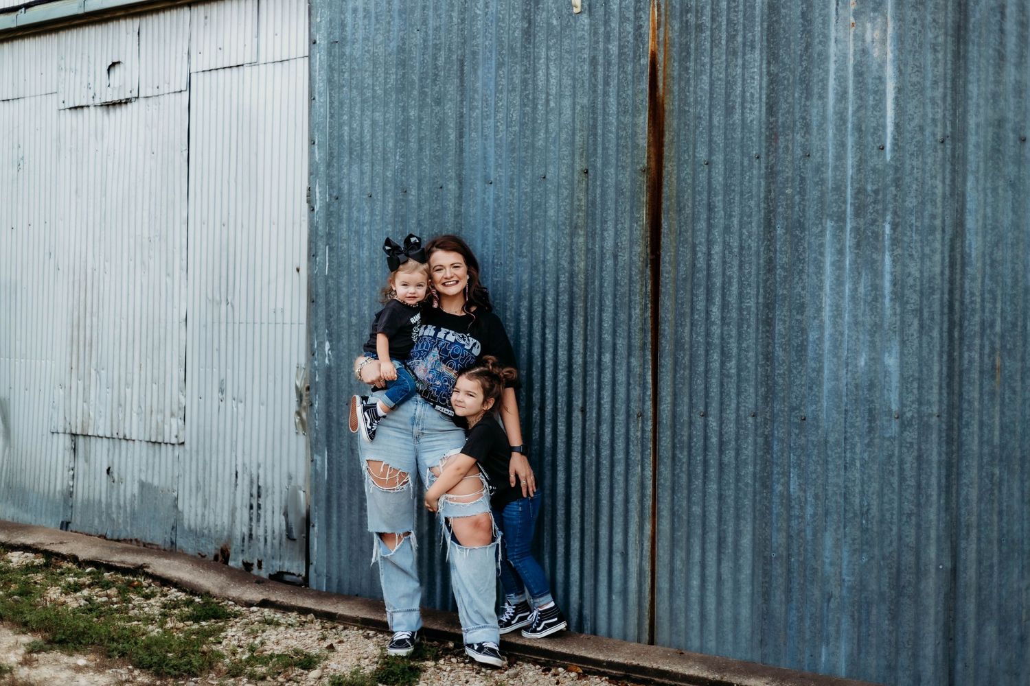 Mother and daughters pose in front of a metal building