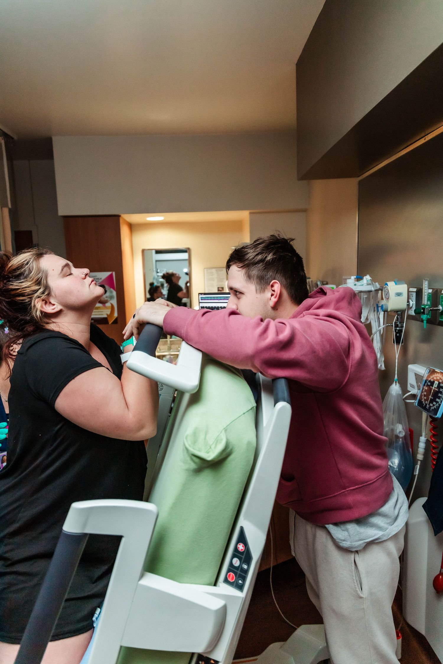 Husband holds wife's hands while she breathes through contractions