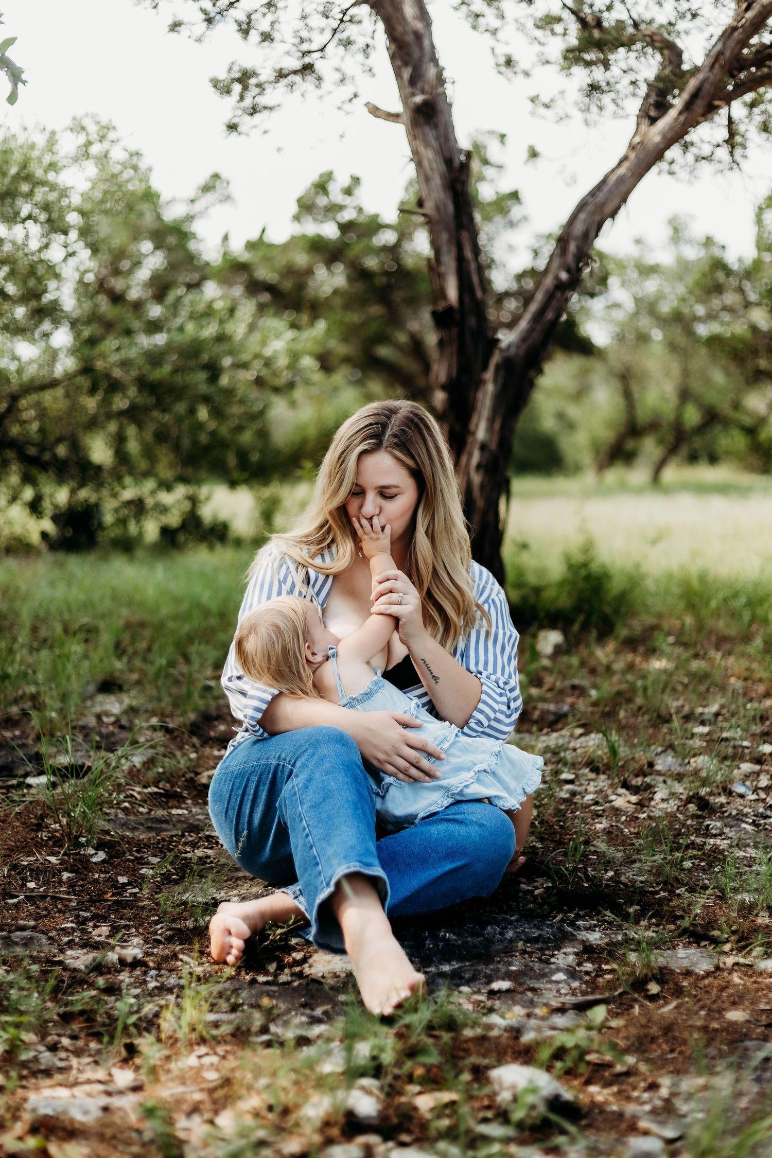 Mother nurses her baby in the outdoors and kisses her hand
