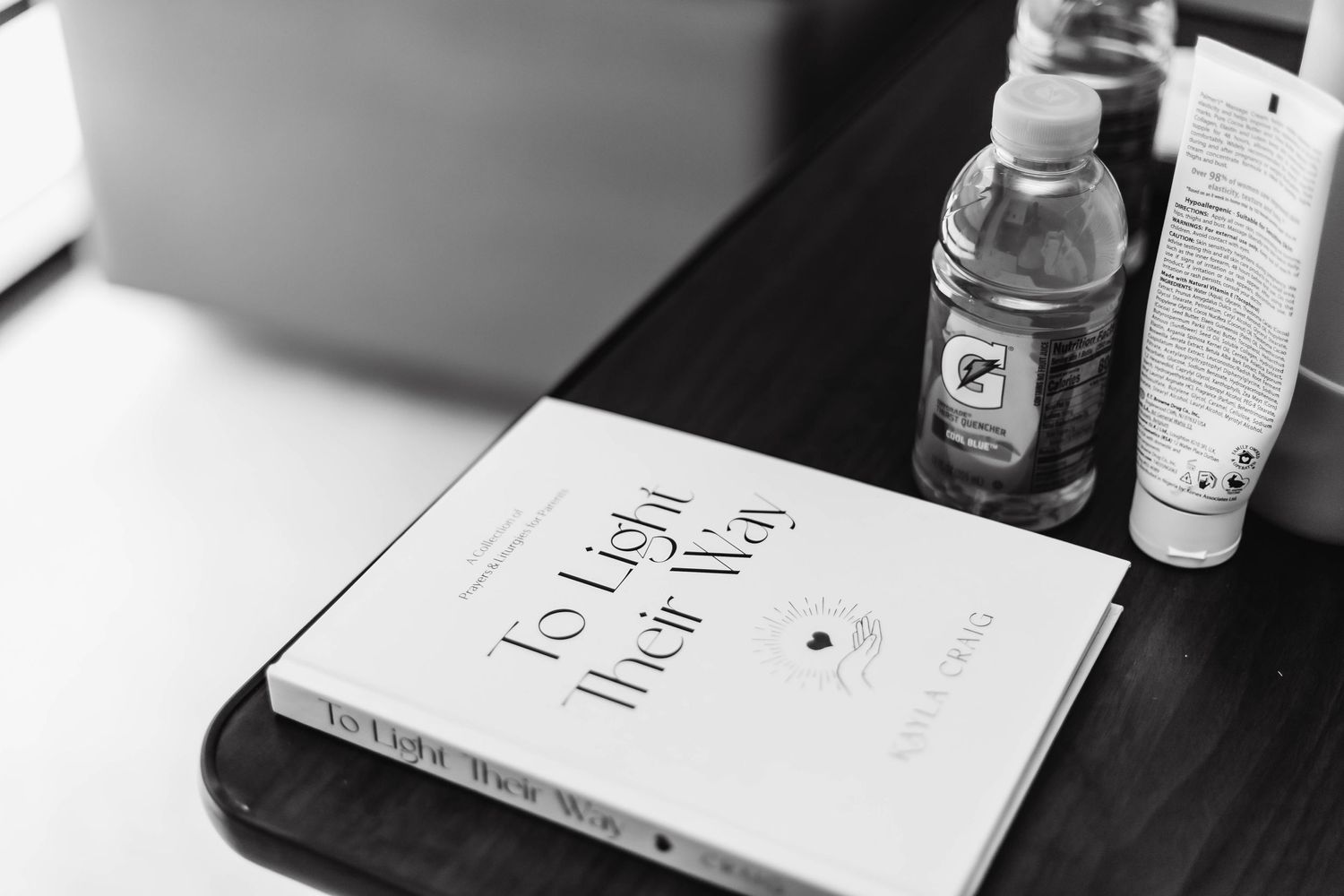 Book, water, and lotion lay on table.