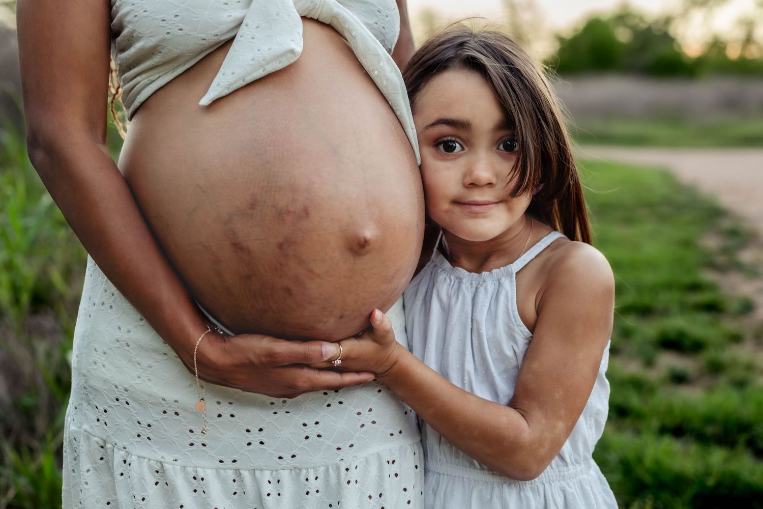 Daughter hold moms pregnant belly waiting on new baby to come