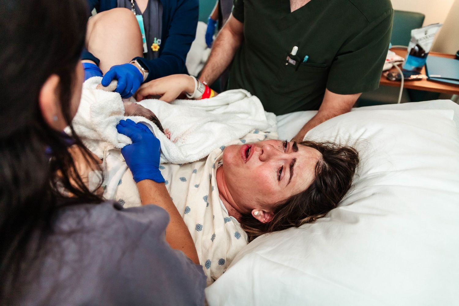 Mother breathes deeply after delivering baby and baby is placed on her chest.