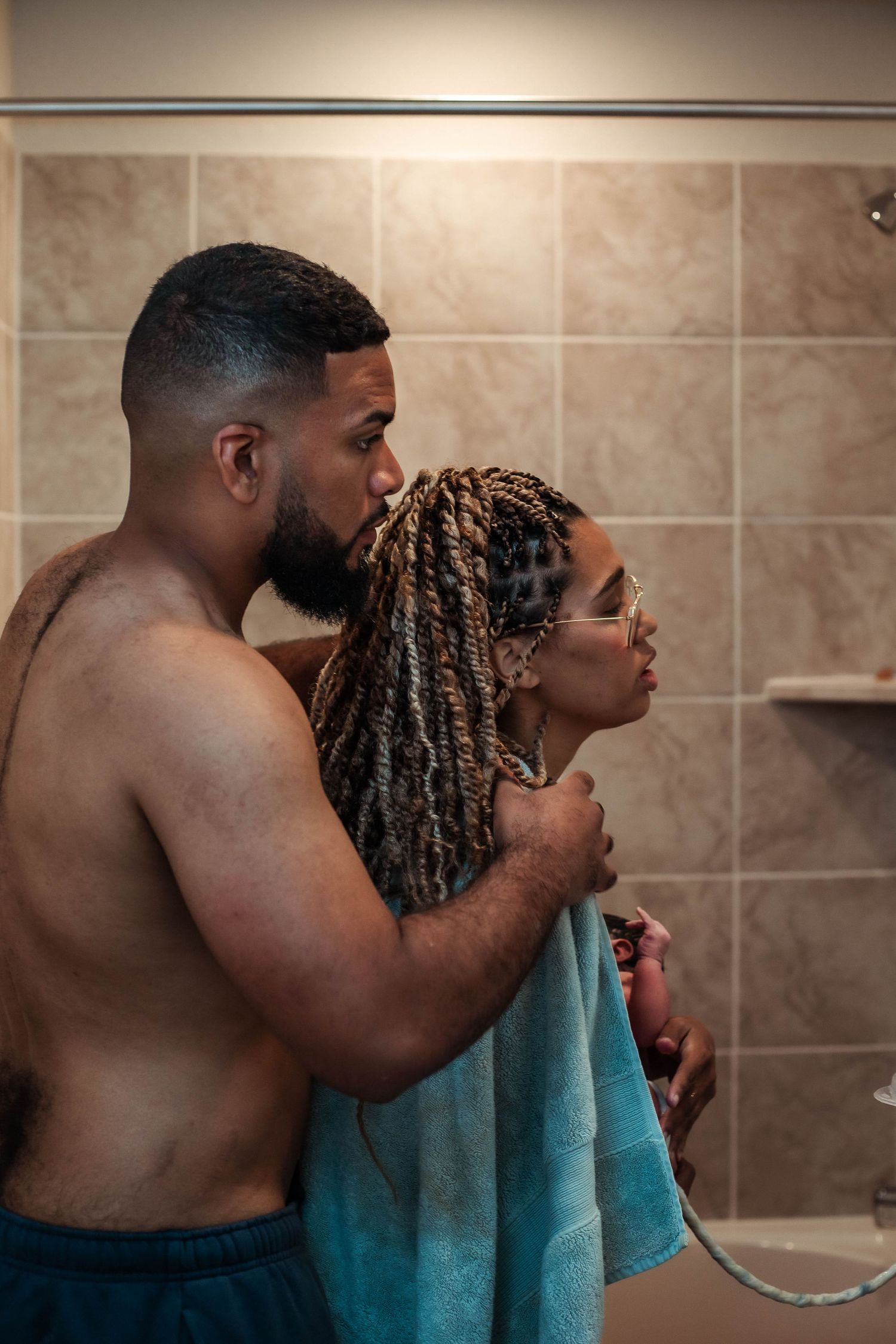 Husband helps cover wife with towel after her free birth in their home.