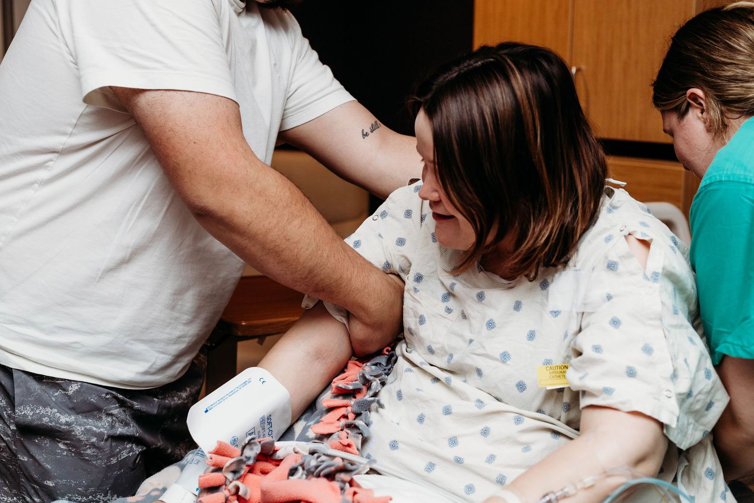 Husband helps wife sit up during labor while nurse adjusts her bed