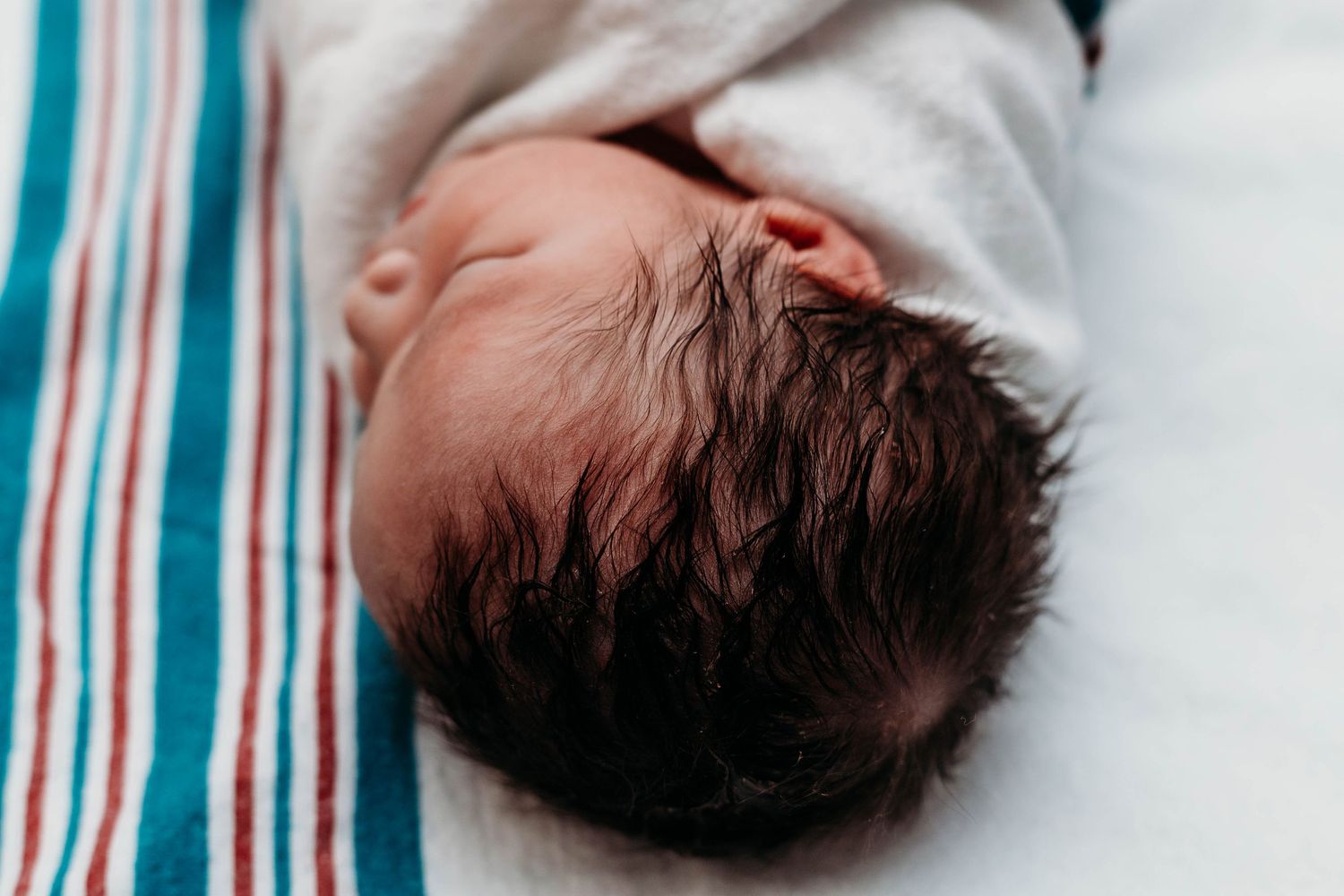 Baby laying in hospital bassinet, focused on baby's hair