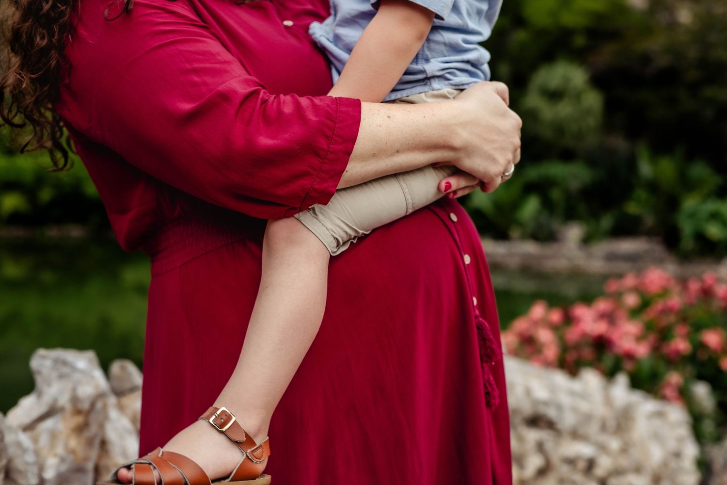 Mother holds older child on top of her pregnant belly