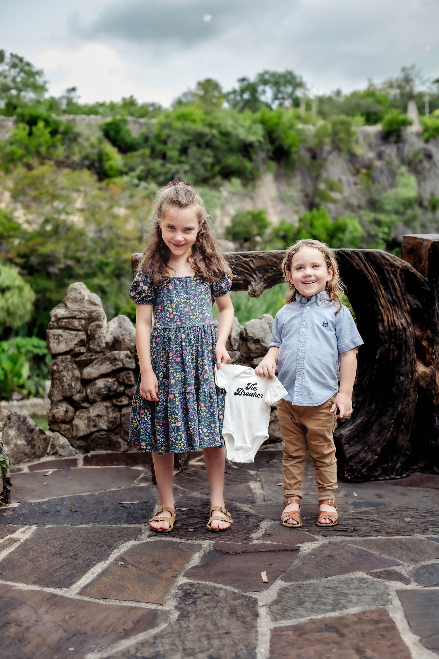 Older siblings hold onesie stating tie breaker