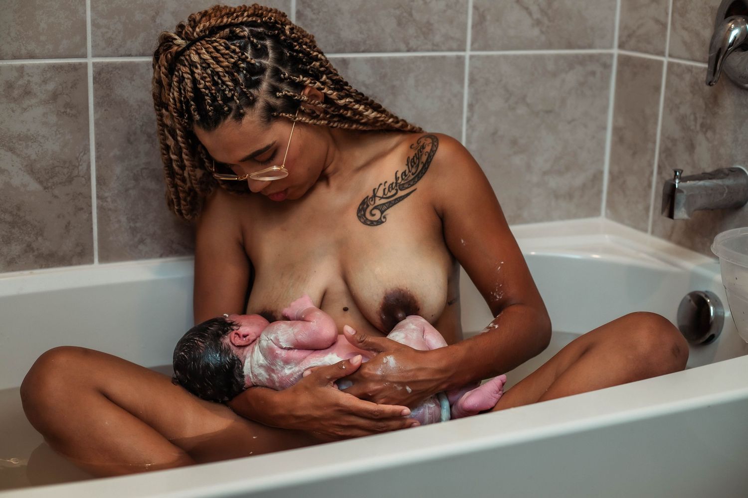 Mother nurses baby in home bathtub