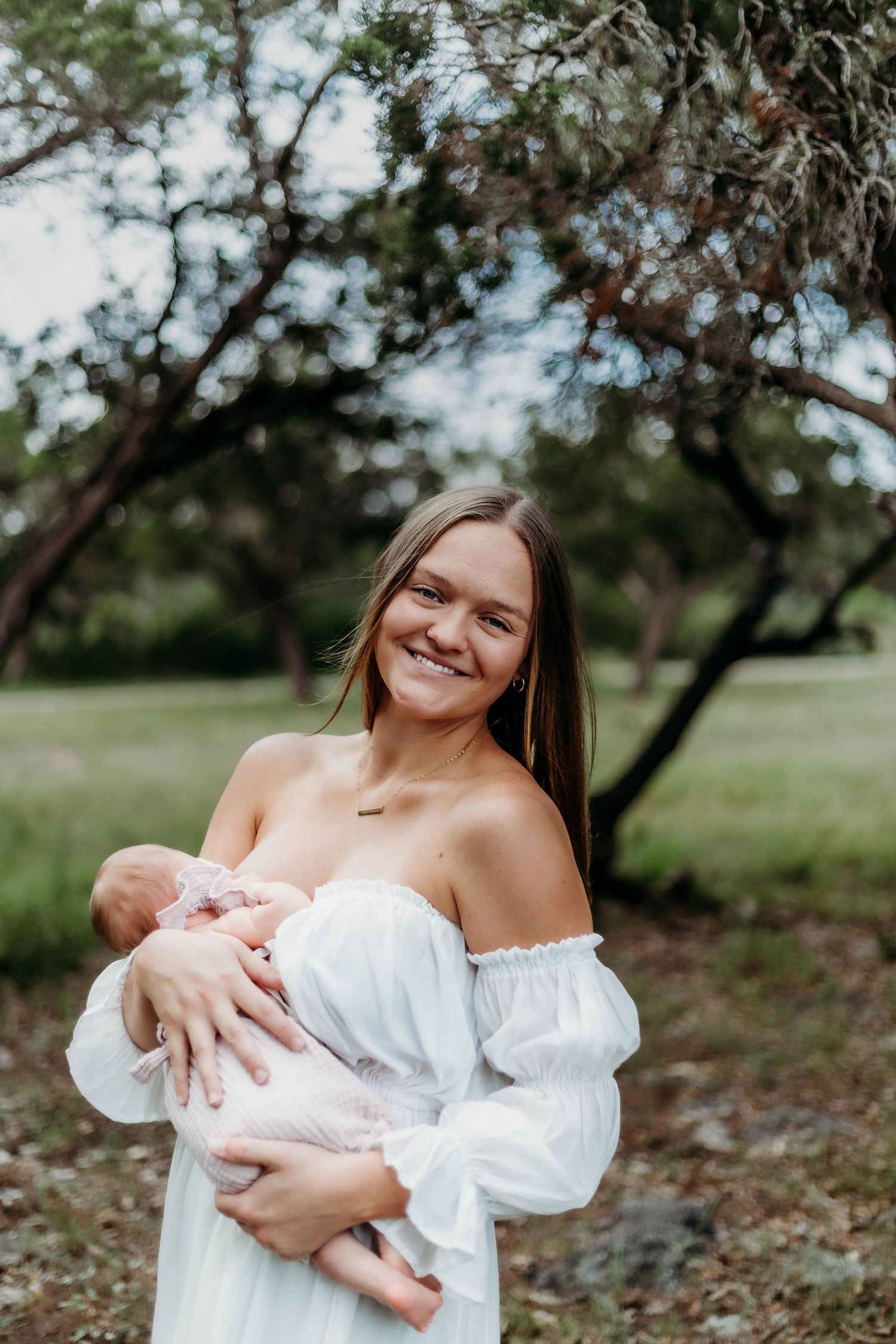 Mother nurses newborn baby outside during session