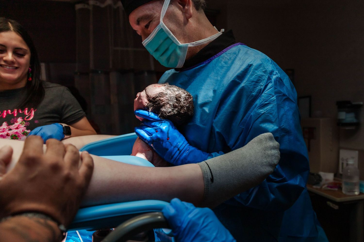 Doctor holds up newly born baby to show mom