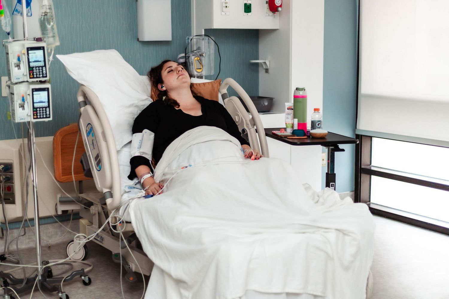 Laboring mother relaxes in hospital bed listening to music during labor