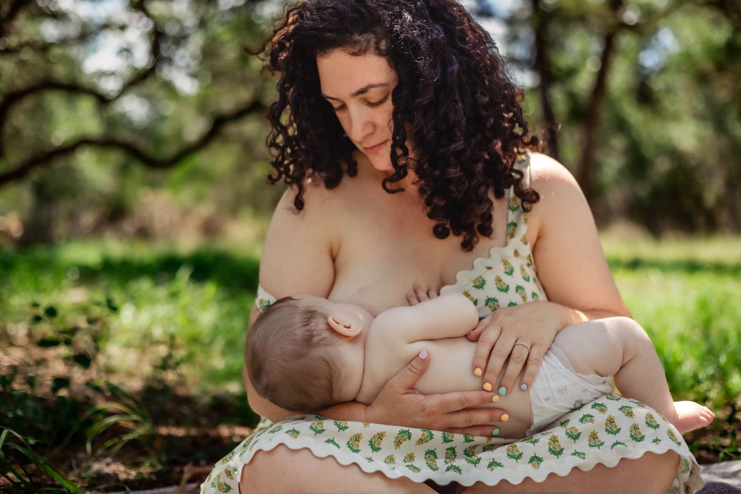 Mother breastfeeds her baby in nature