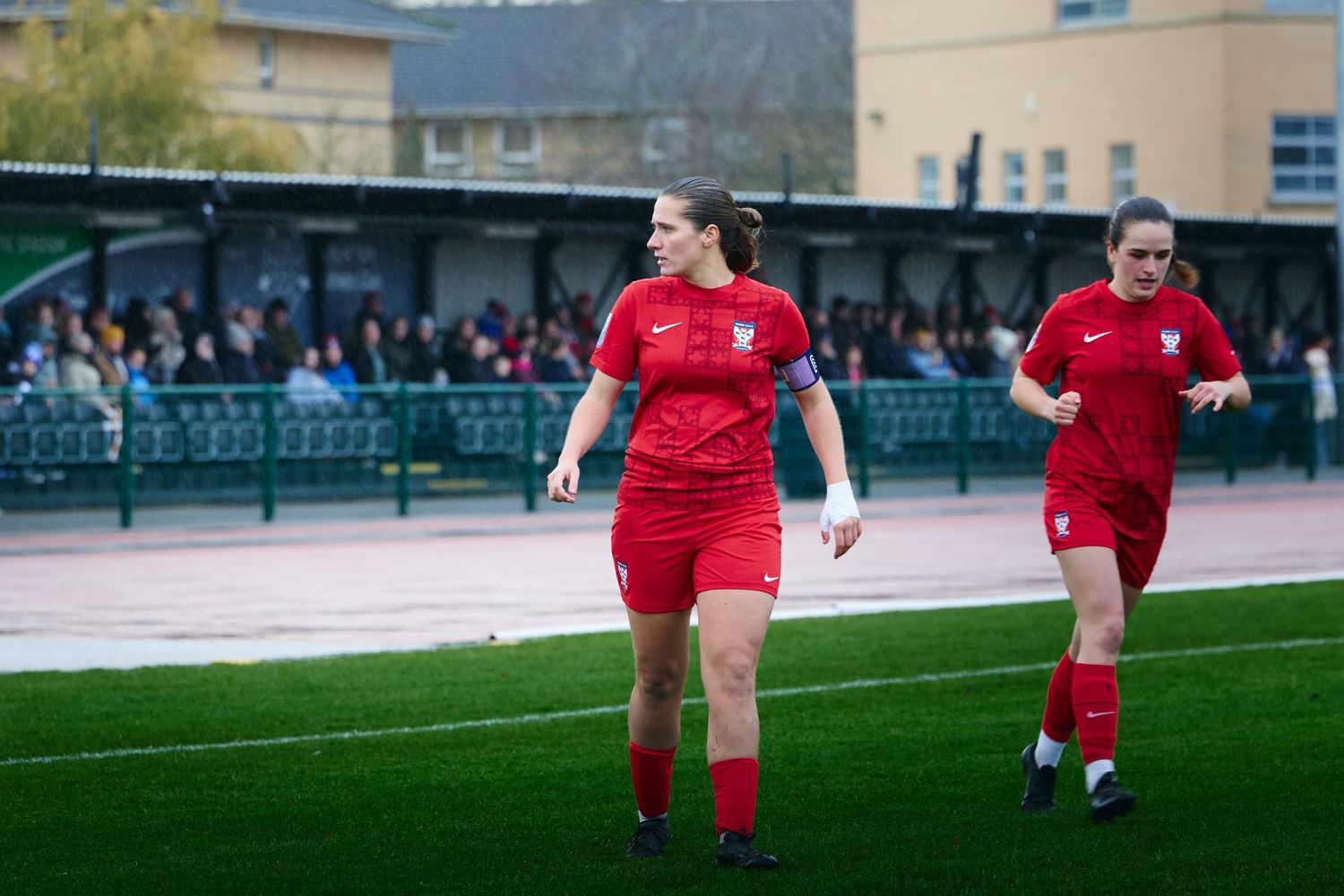 Rugby players in red jerseys run across a sports field during a match or training session.