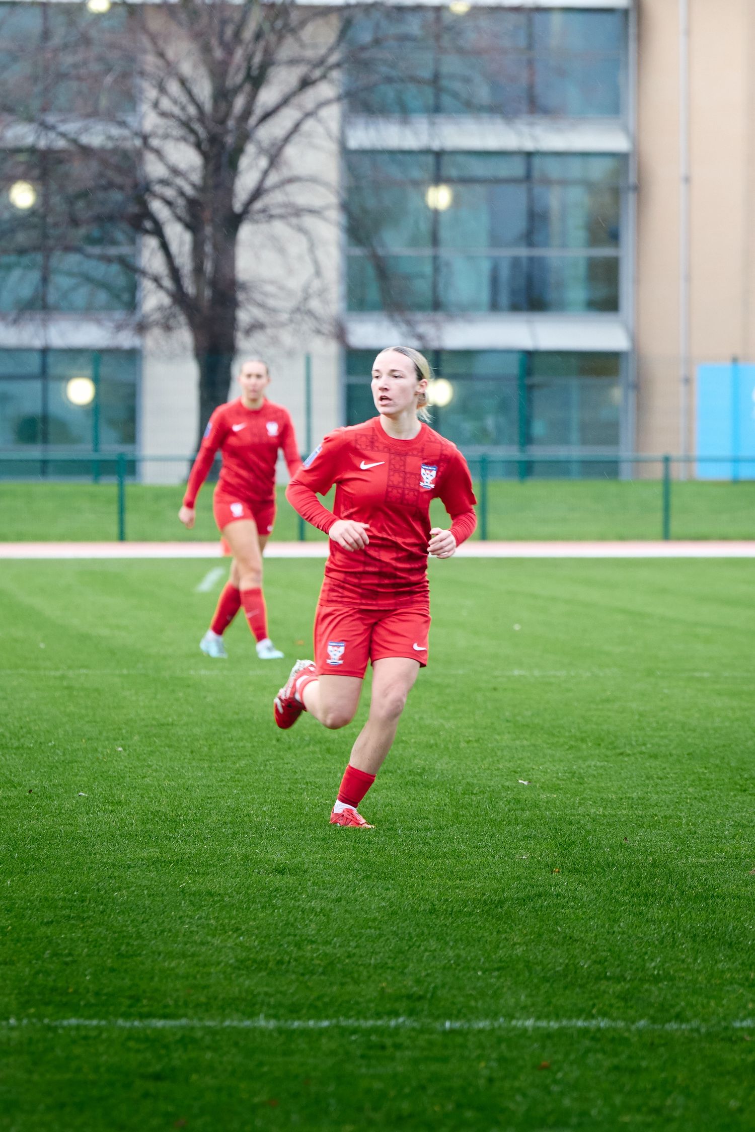 Soccer player in red uniform makes a sliding tackle on green grass field during training session.