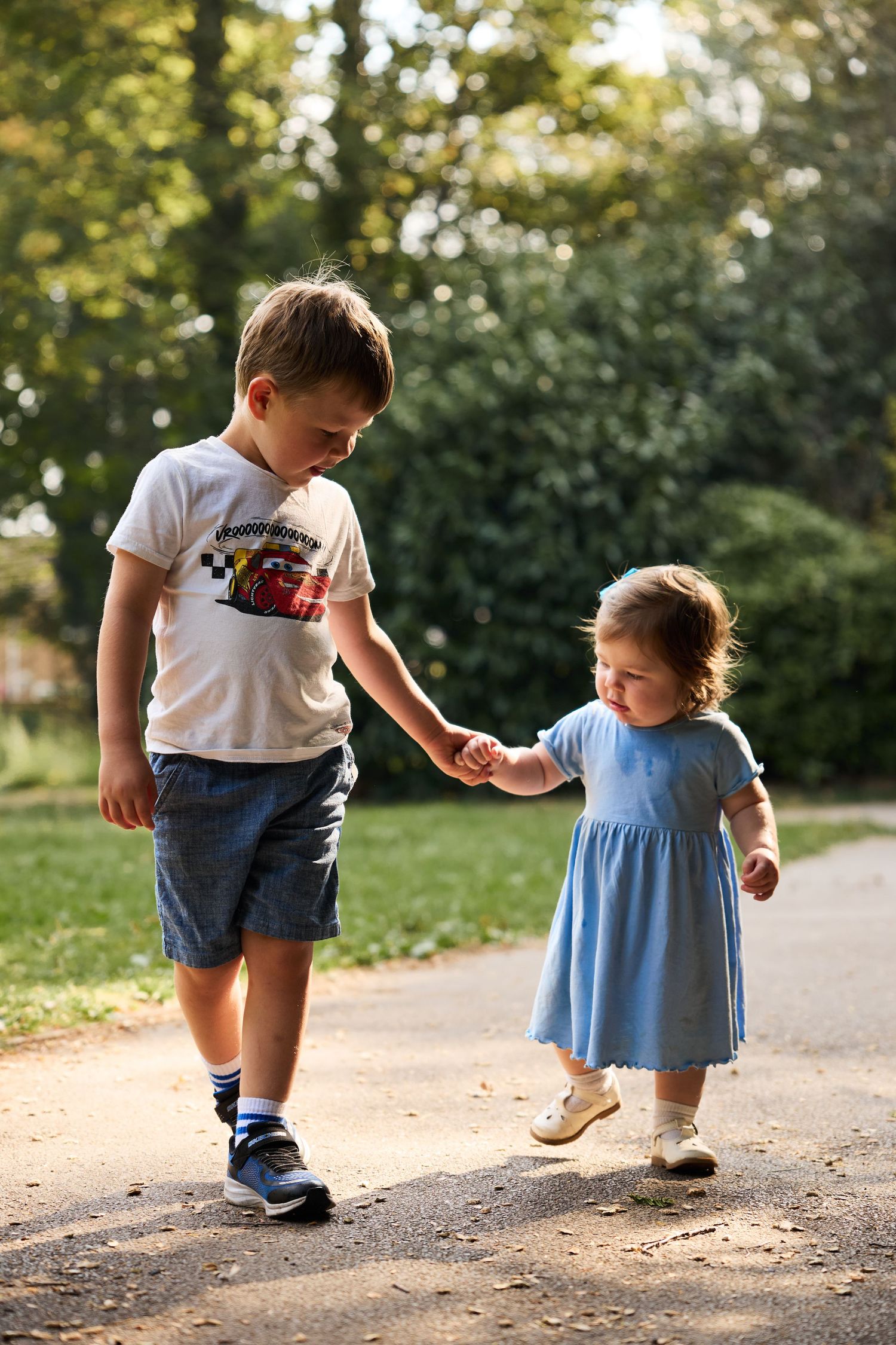 Children walk together on a path while playing during a sunny afternoon outdoors.