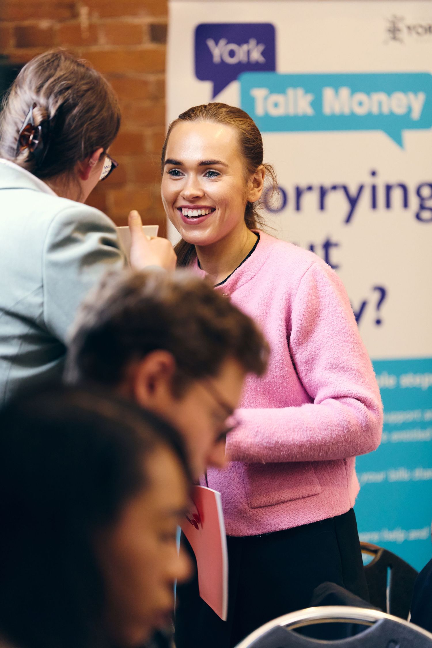 Young woman in pink sweater smiling at a York Talk Money financial advice event.