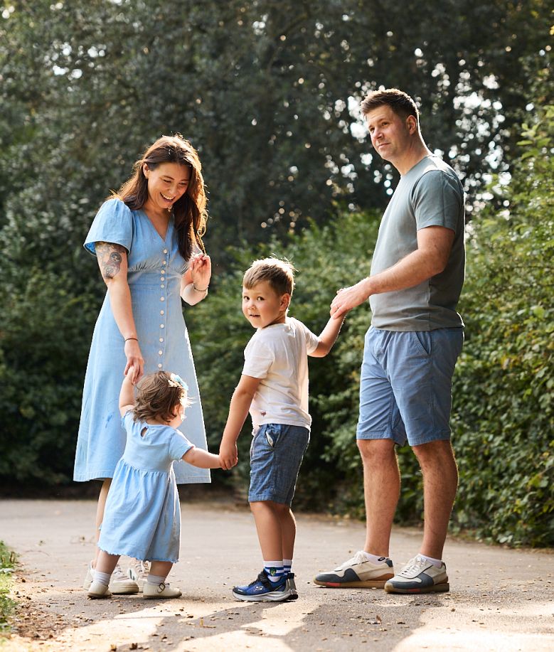 Family members in coordinating blue outfits walk together on a path during a photo session.