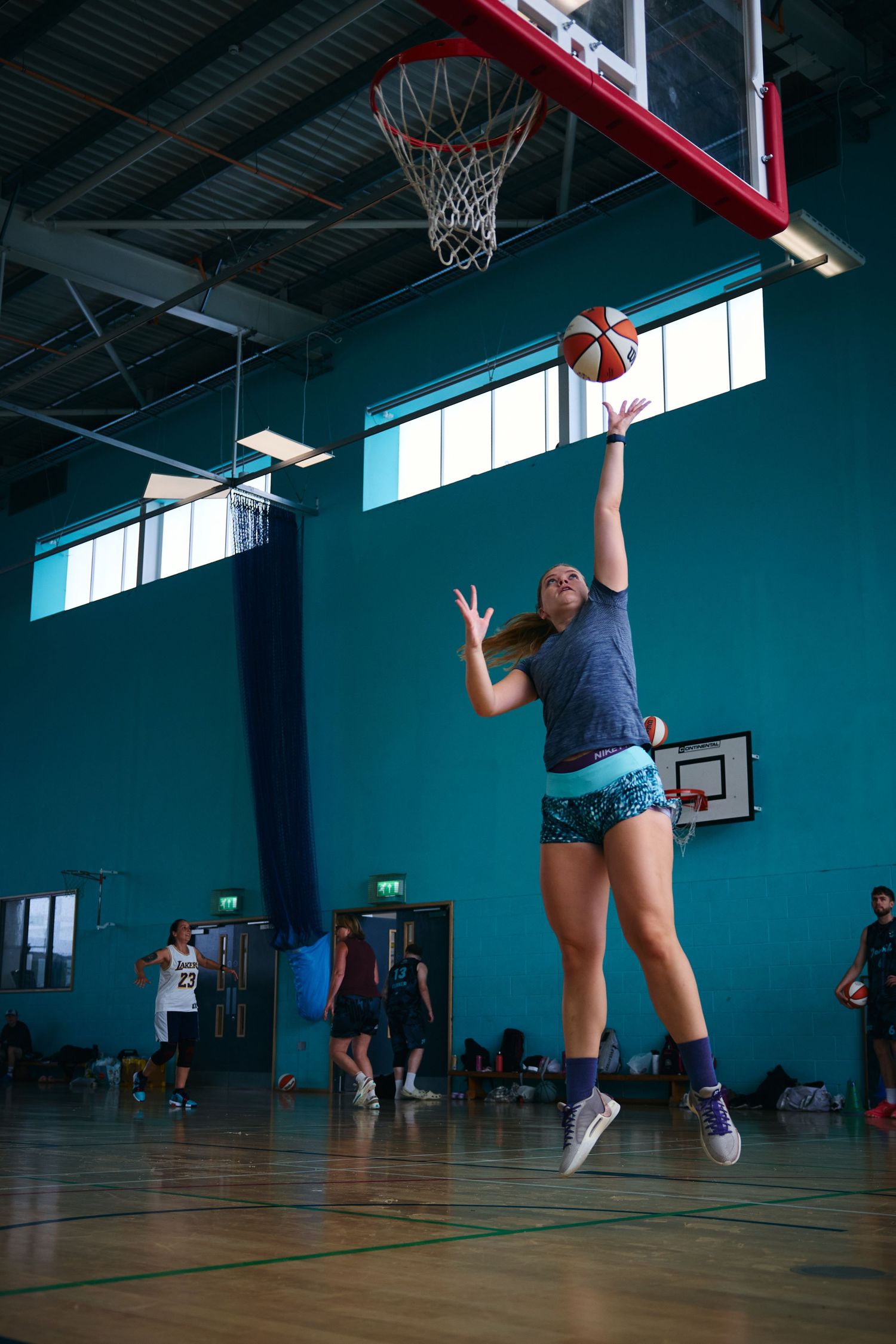 Series of action shots showing basketball layup practice in blue-walled indoor gymnasium.