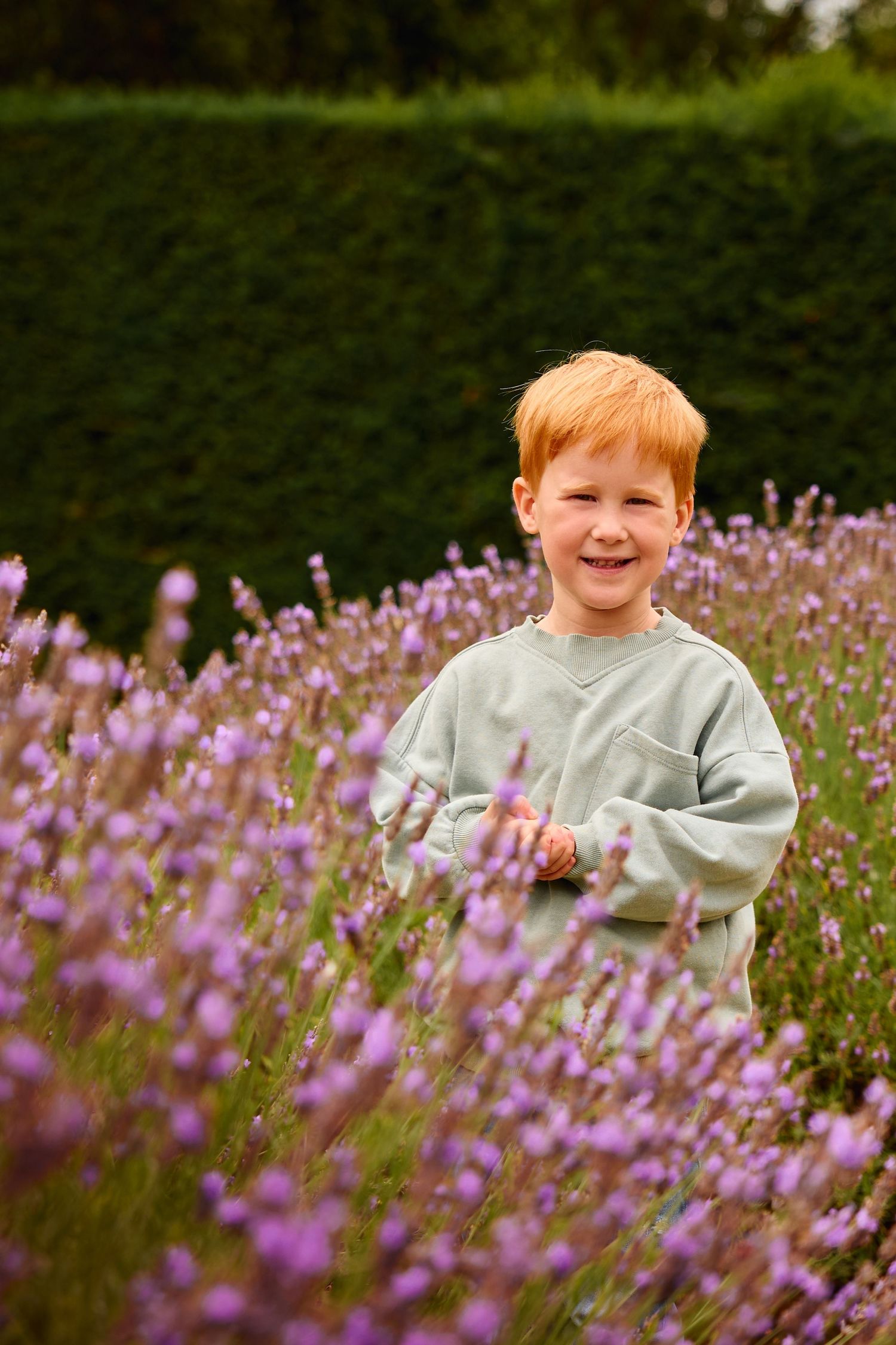 Child playing among vibrant purple wildflowers in a garden setting.