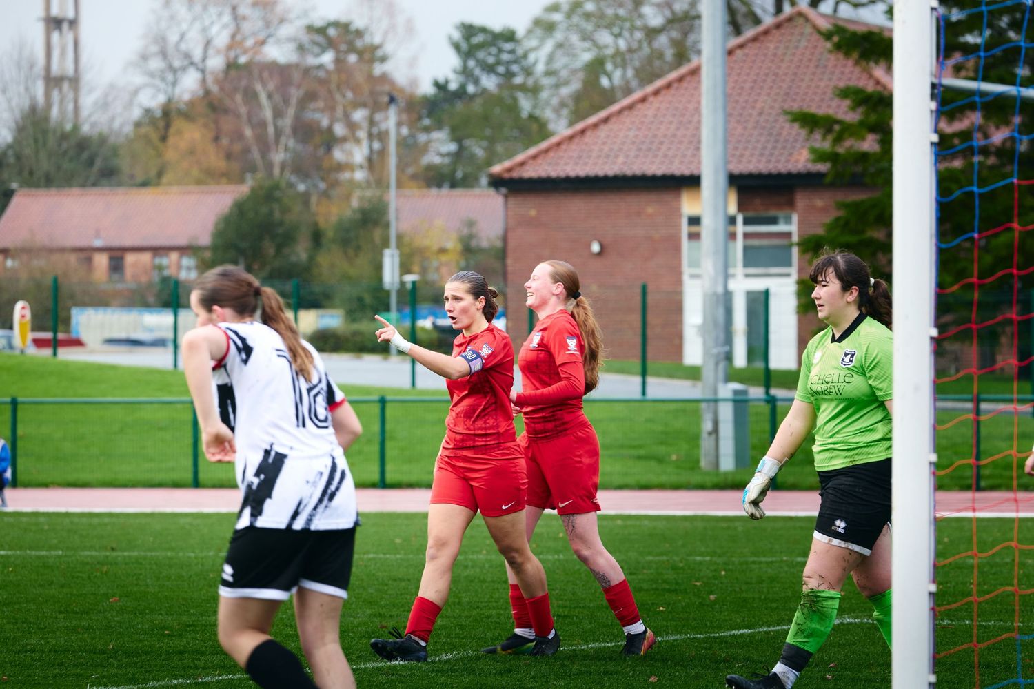 Soccer players in red and white uniforms compete for the ball during an intense match on a grass field.