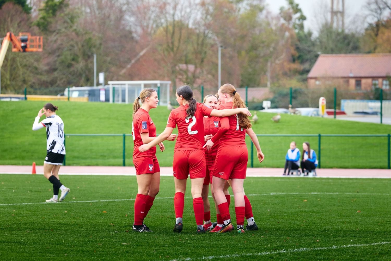 Soccer players huddle together on a green grass field during a match.