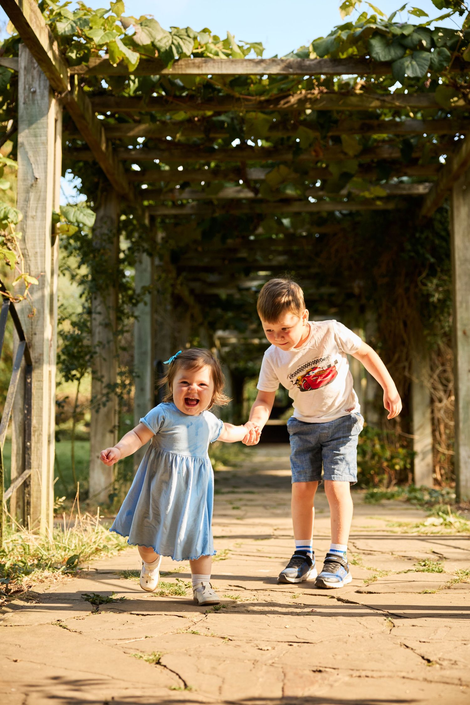 Joyful family playtime sequence under vine-covered garden pergola.