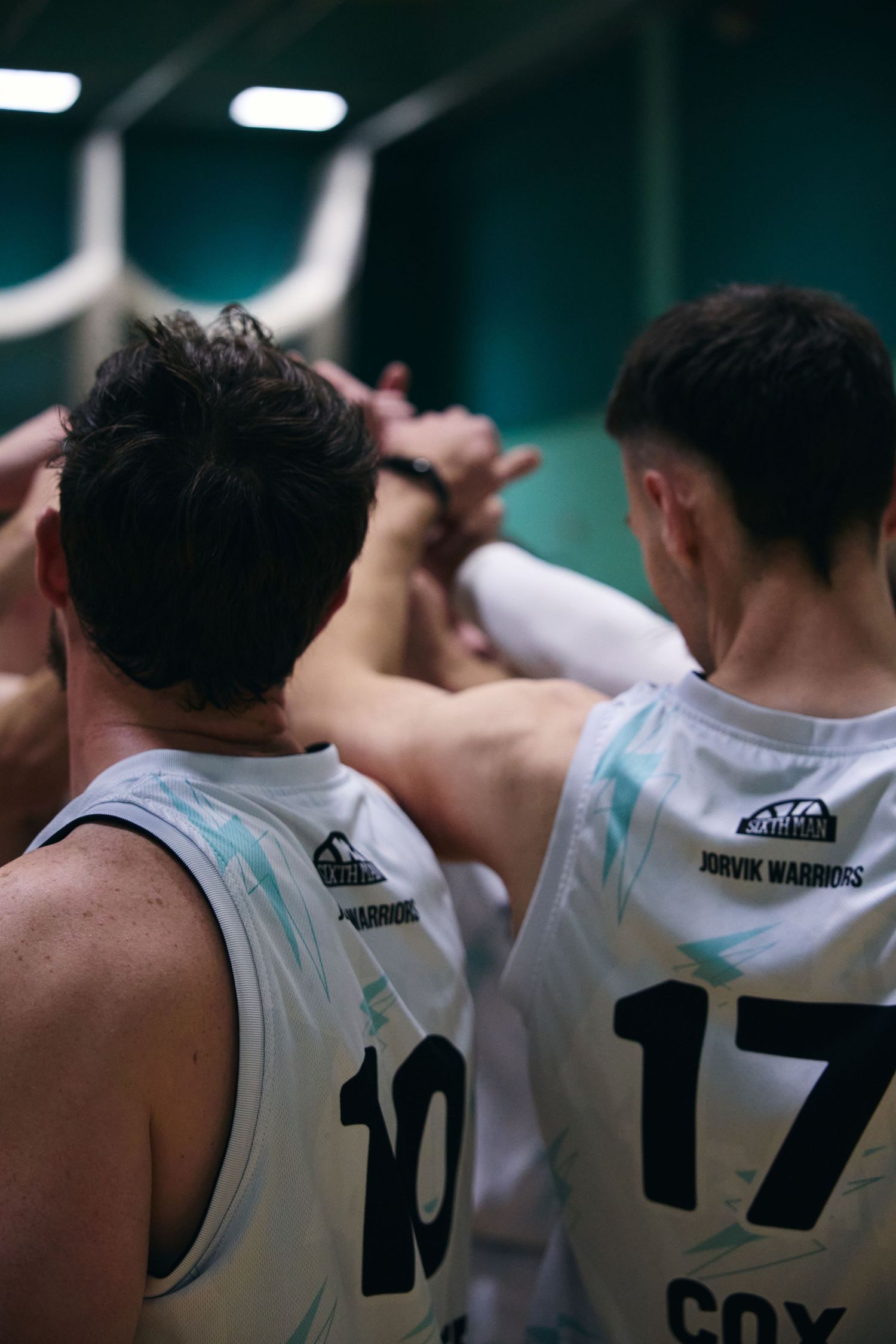 Basketball players in white jerseys with numbers stand together during a team moment.